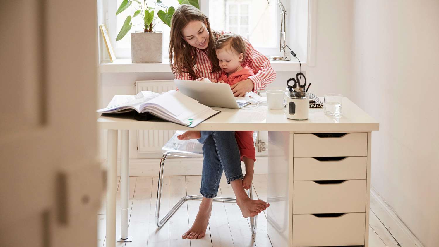 A mother working from her home office while holding her daughter