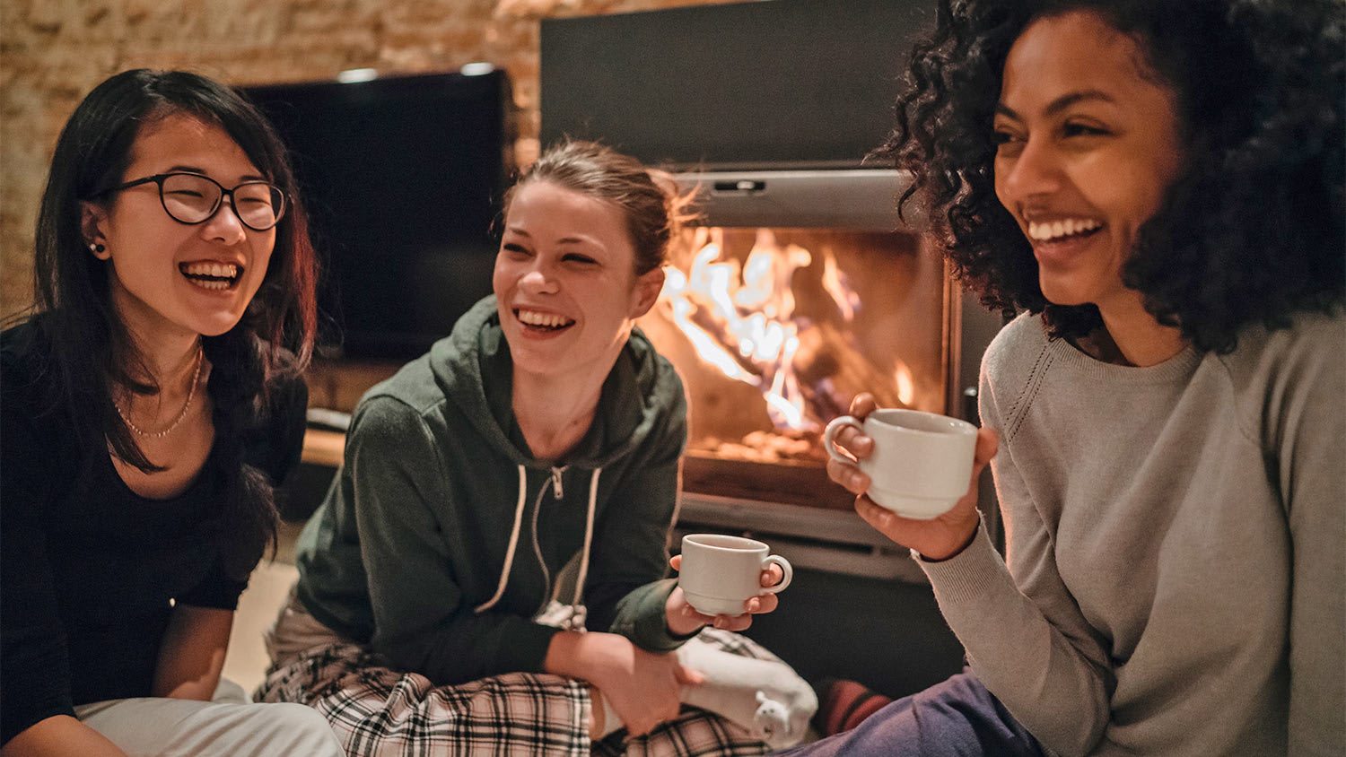 Women smile in front of fireplace