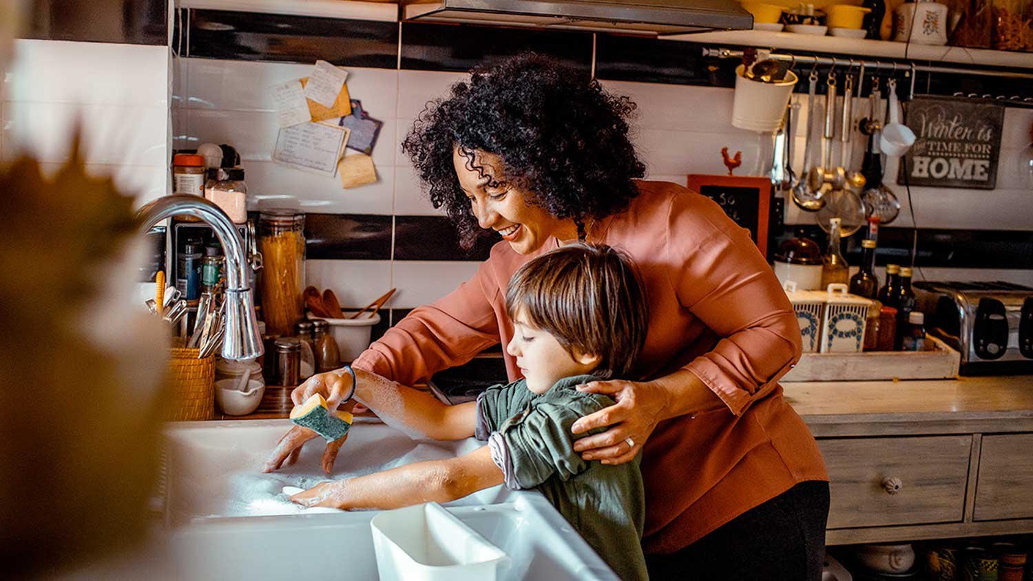 A mother and child wash dishes