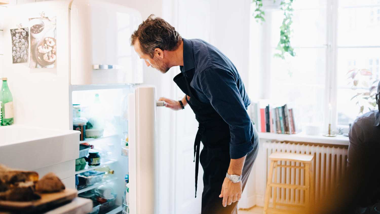A mature man looking into the refrigerator