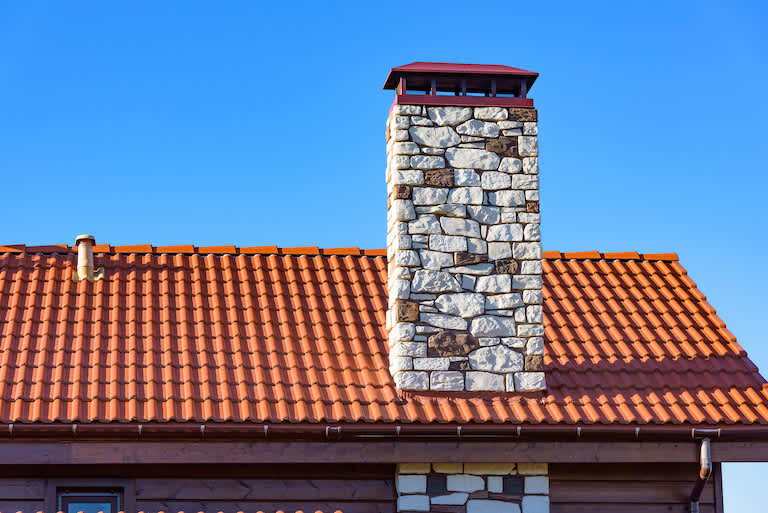 shot focusing on orange roof and red gutters with stone chimney