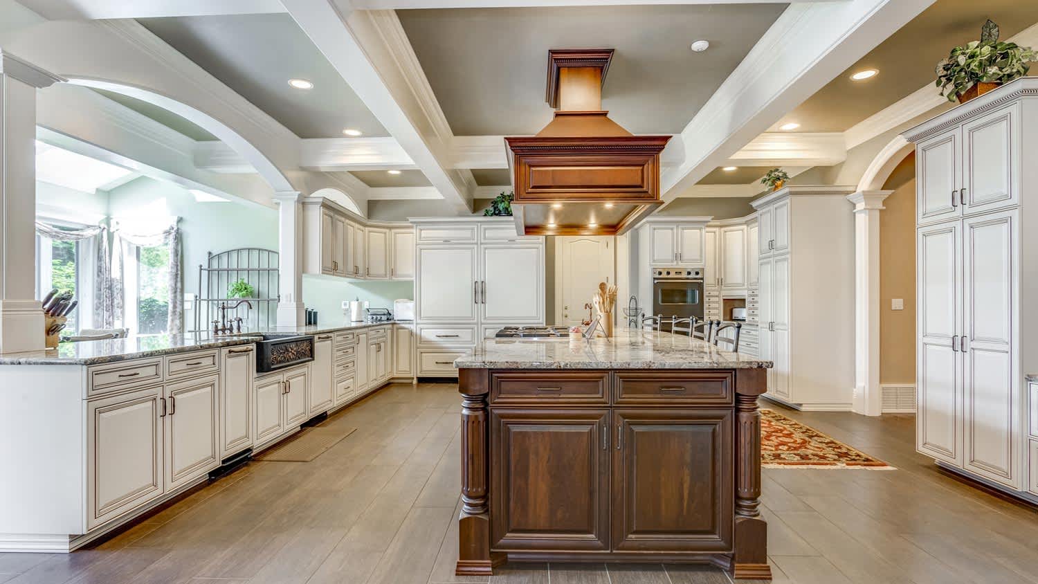 A spacious kitchen with a wooden island and coffered ceiling