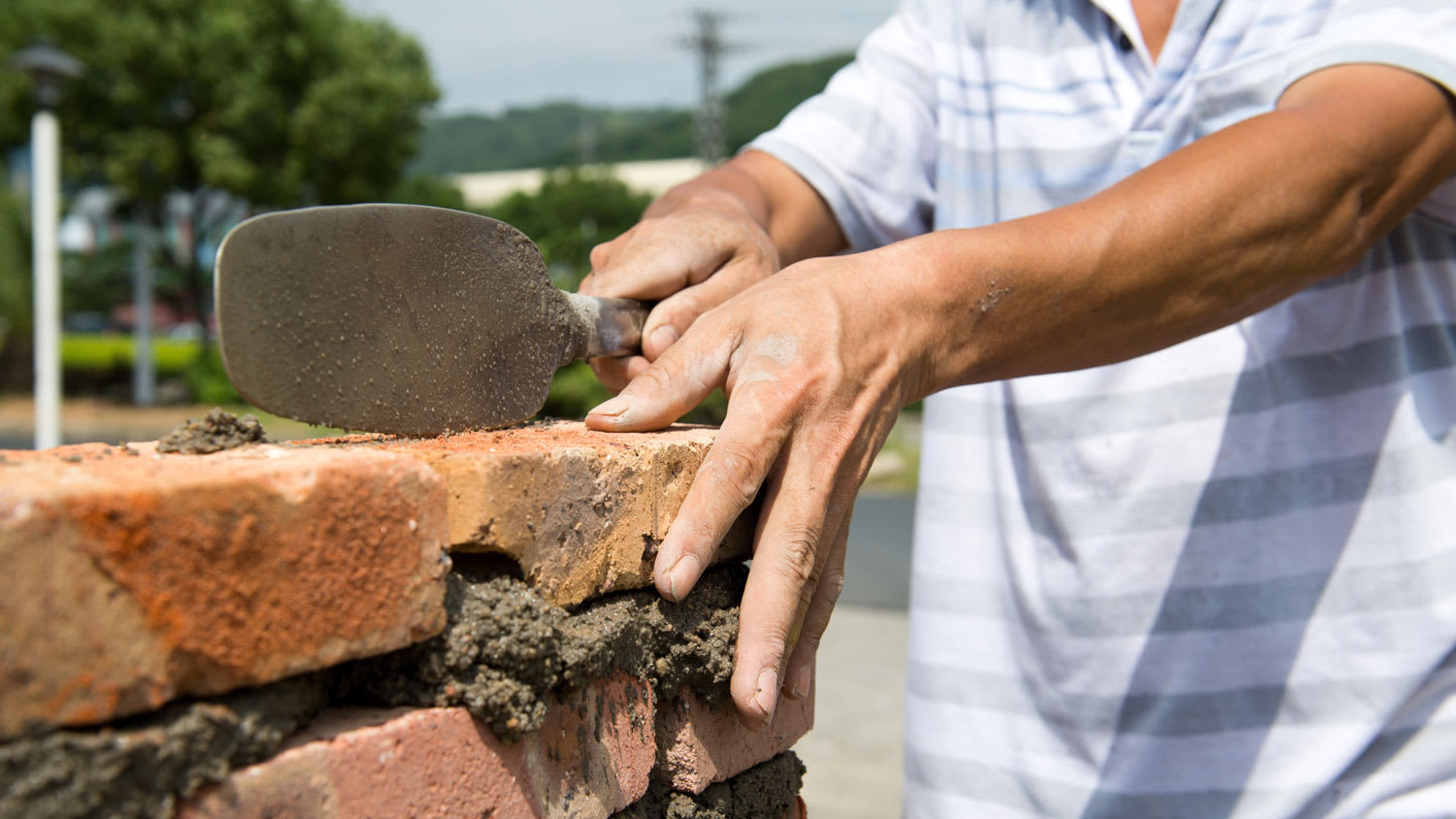 A worker repointing a brick wall
