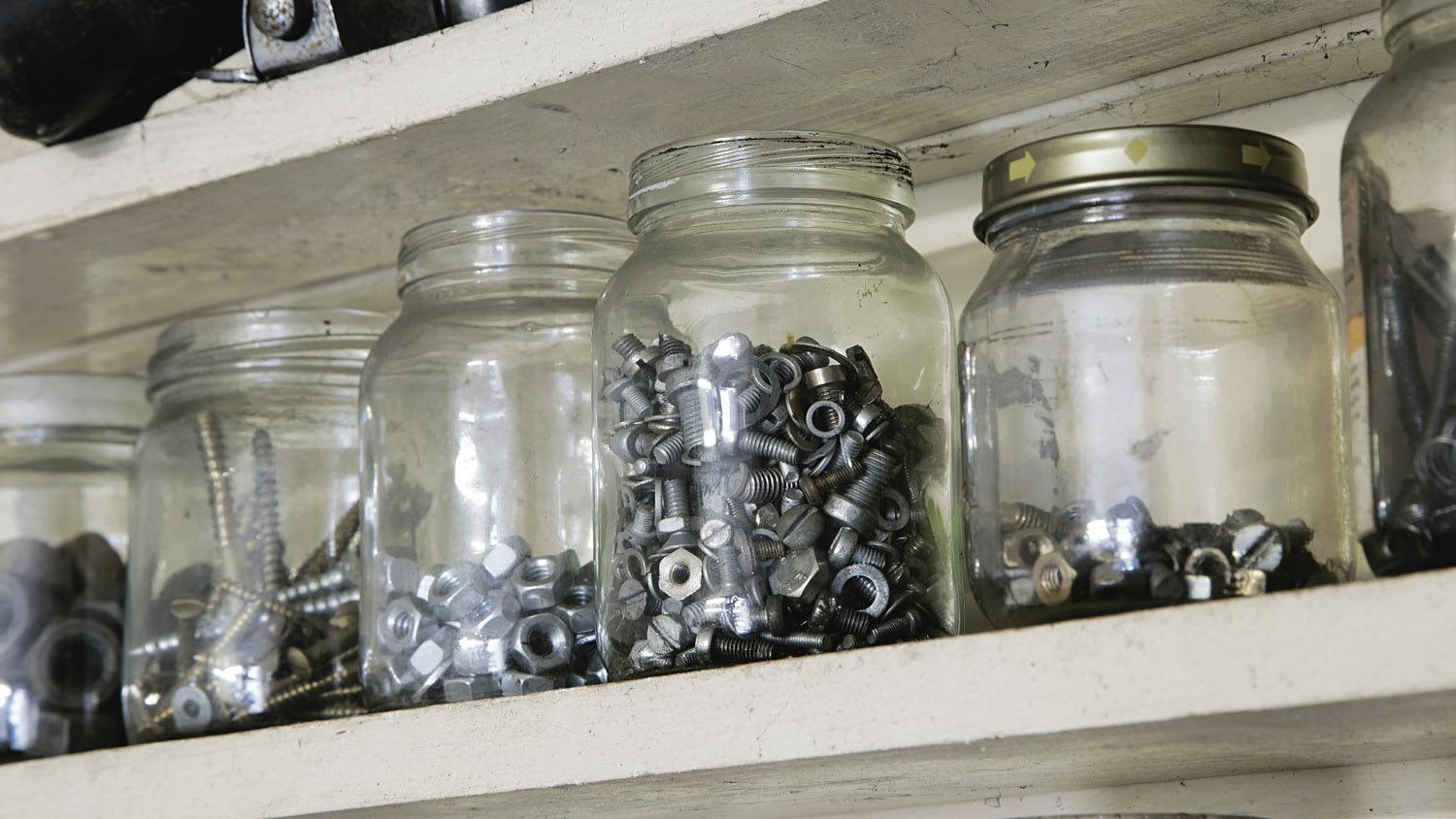 Vintage jars on a shelf containing nuts, bolts and screws