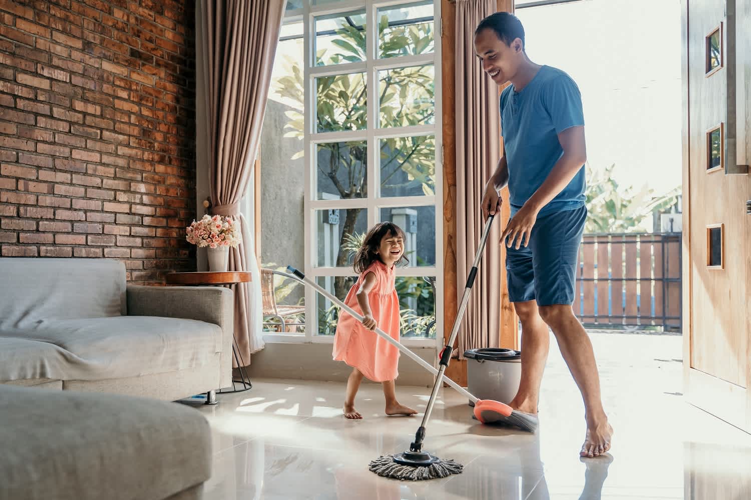 Father and daughter mopping living room floor