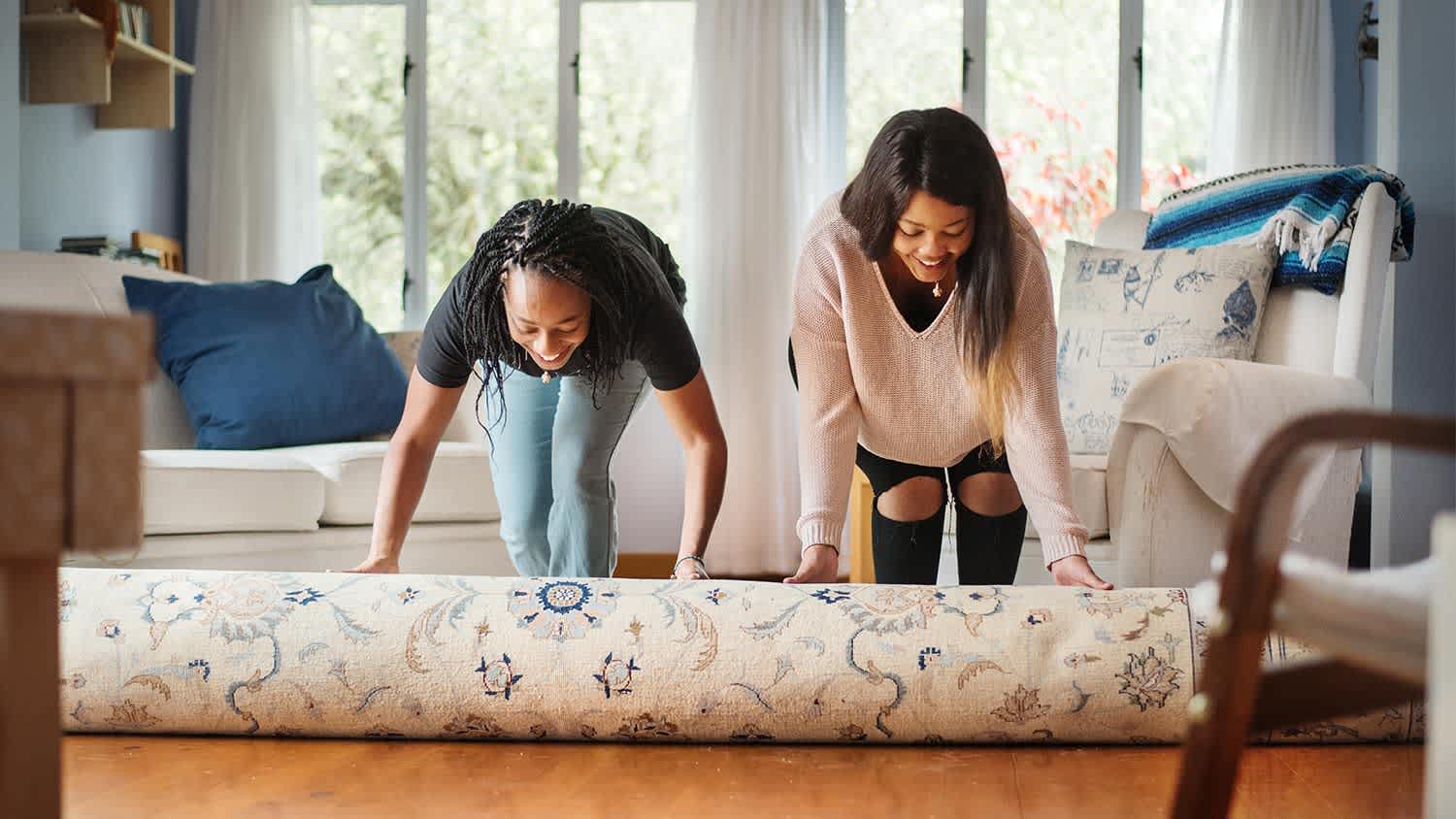Girlsr olling up rug on wood floor
