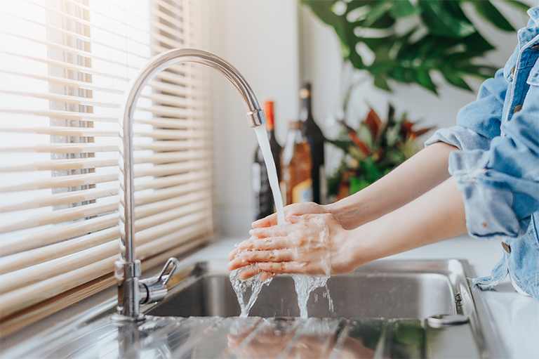 Woman washing hands in kitchen sink
