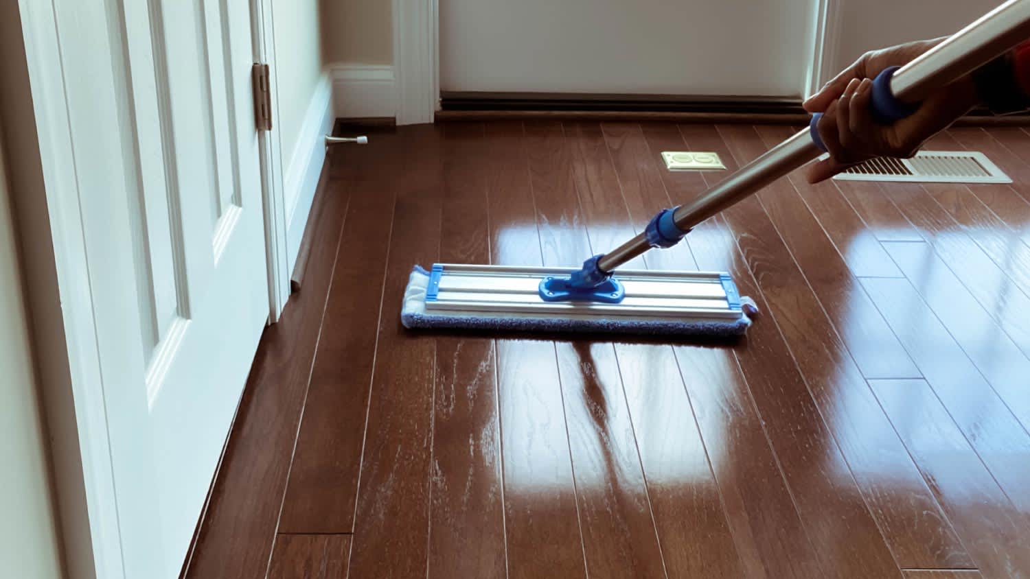 A woman mopping corner of hardwood floor