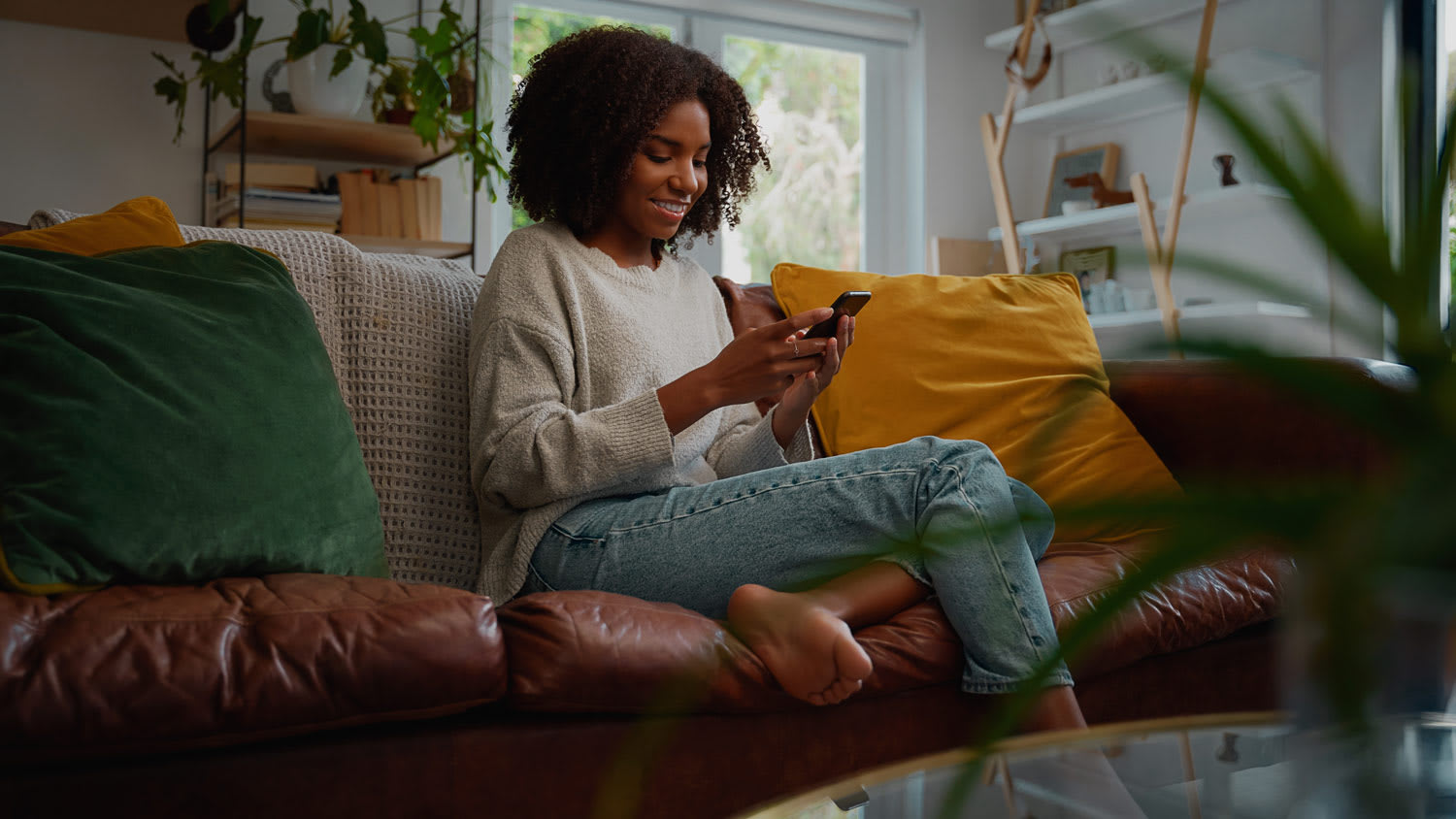 A young woman using her phone while sitting on the sofa