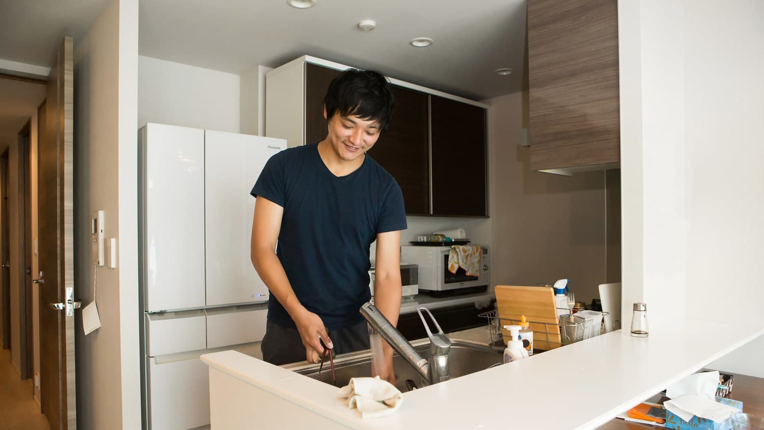 A man washing his coffee mug in the kitchen