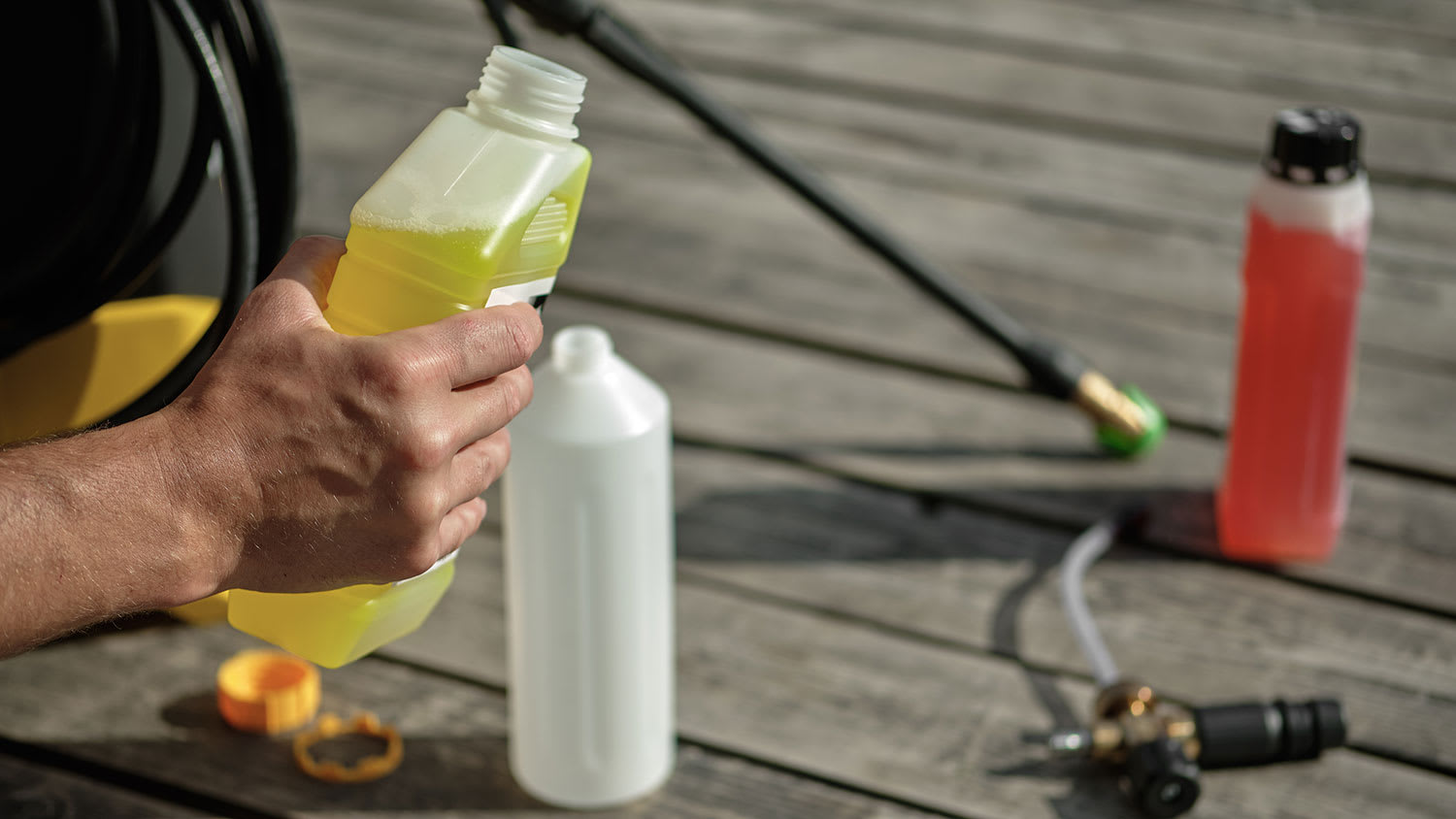 Hand holding container with pressure washer cleaning solution