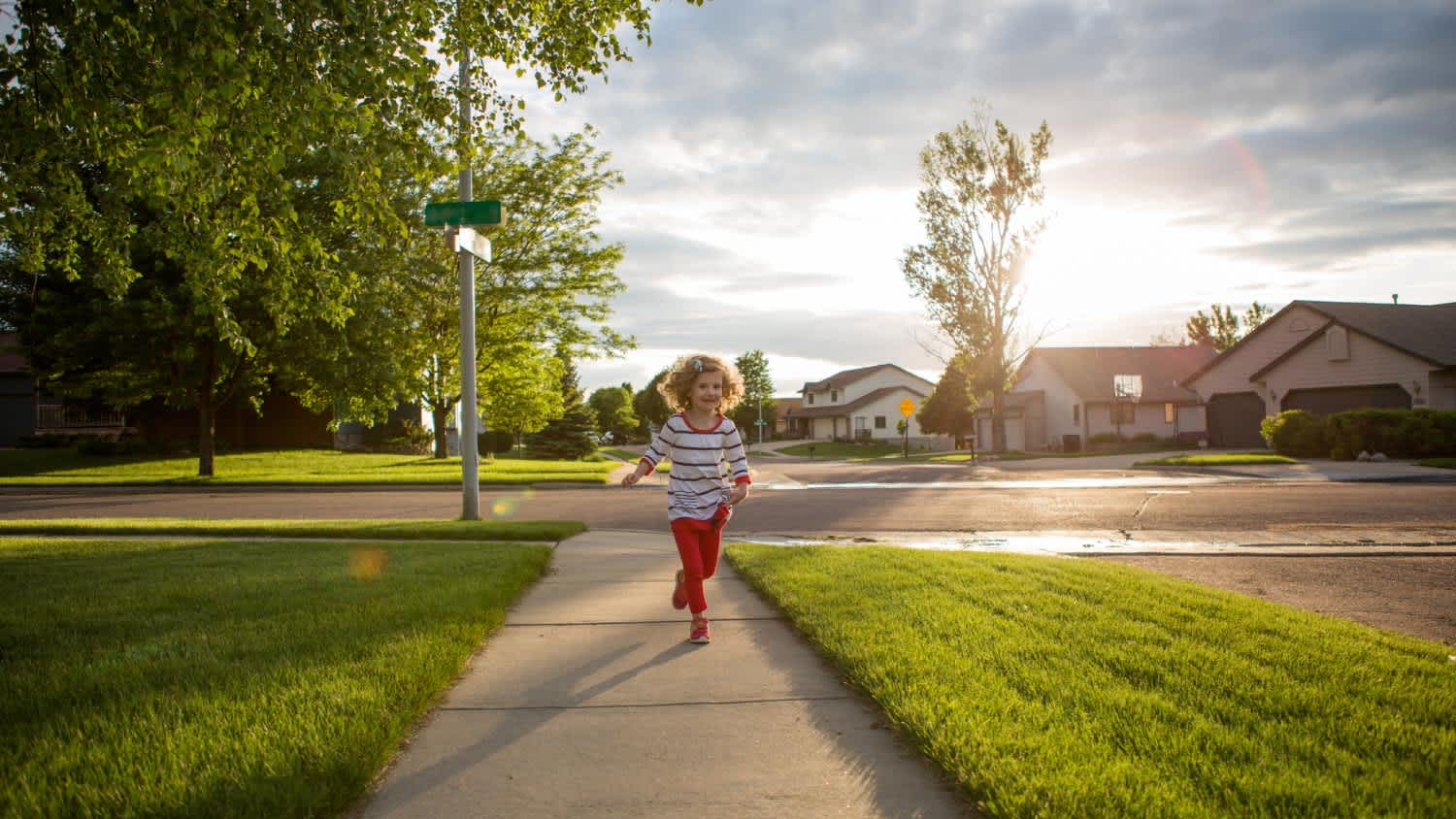 A little girl running down a sidewalk