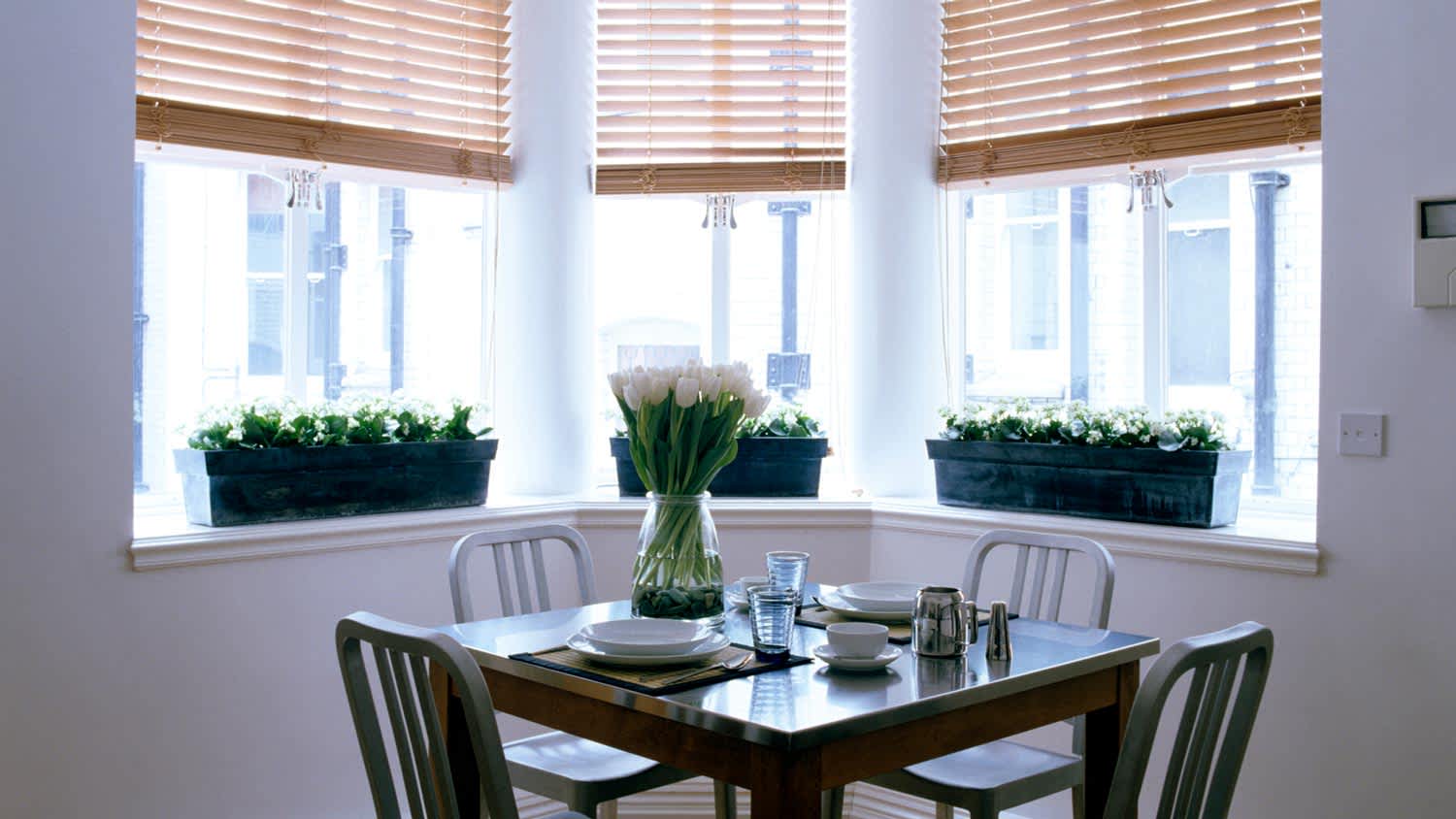 A dining room with a bay window with blinds