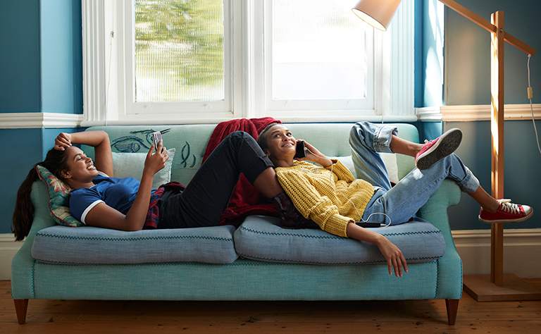 Two girls laugh in room with dark walls and light trim