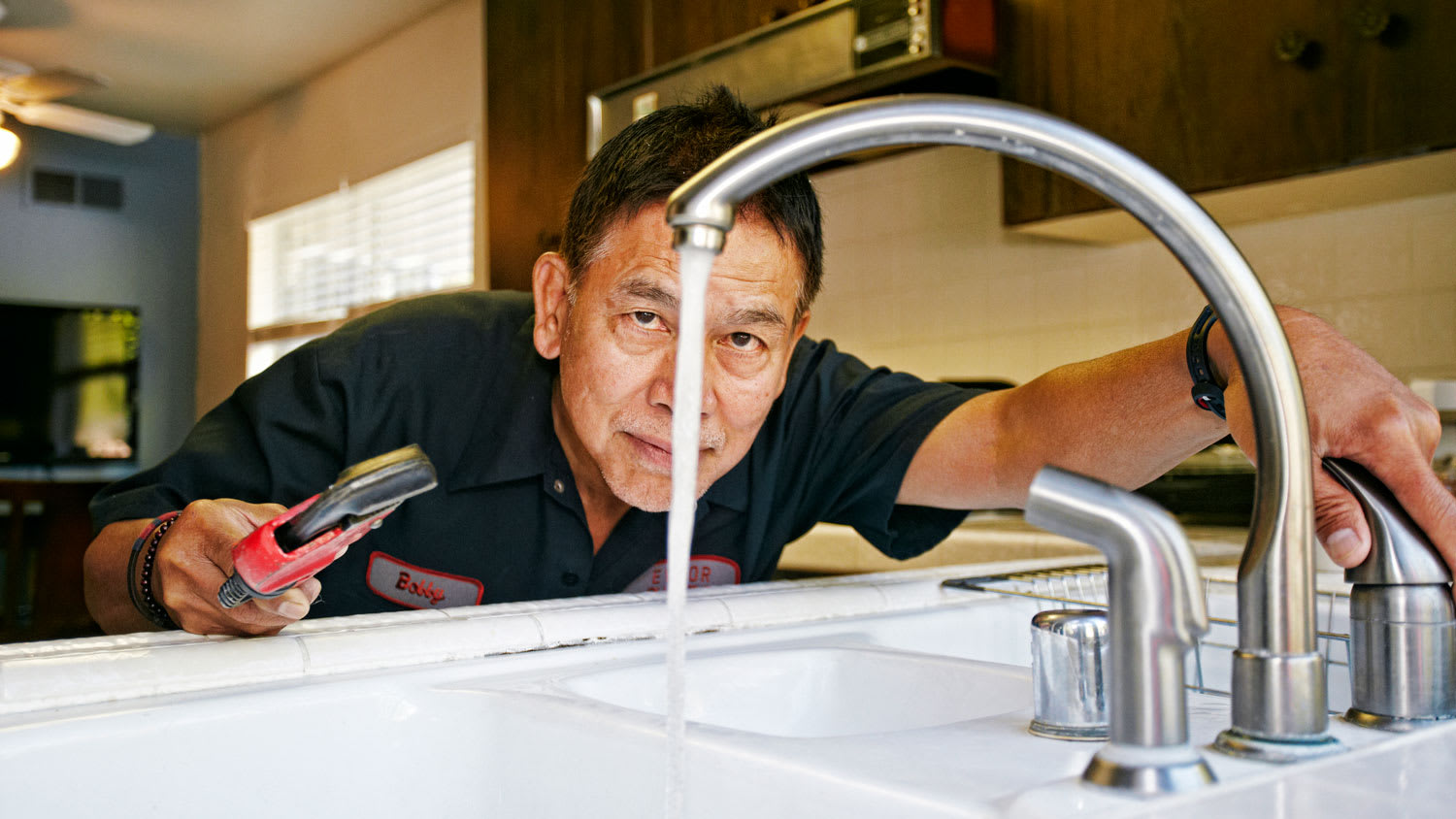 A plumber examining water pressure at a house’s sink