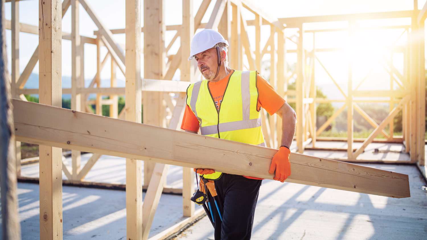 A builder working on a wooden frame house