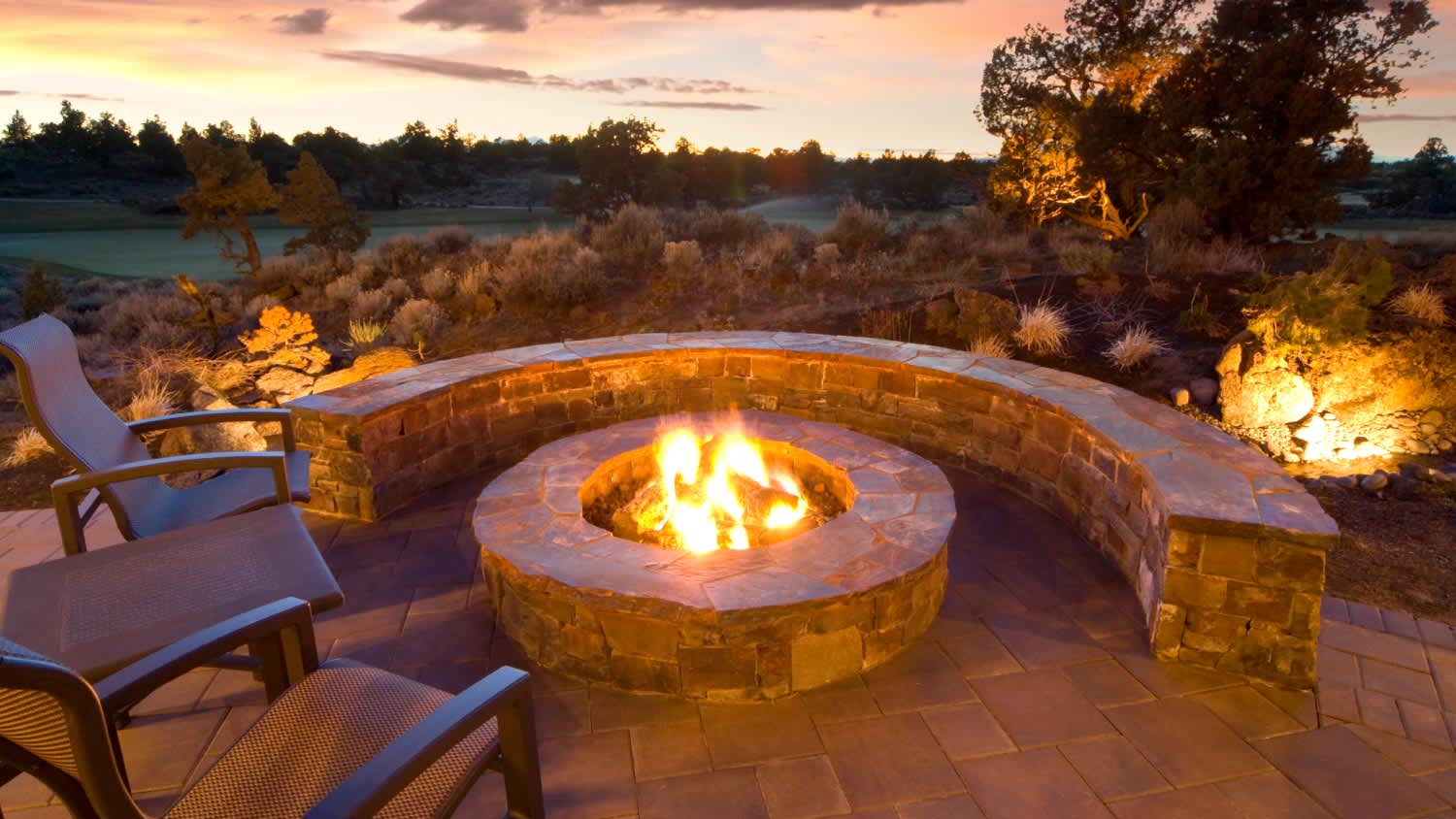 A stone fire pit with outdoor chairs