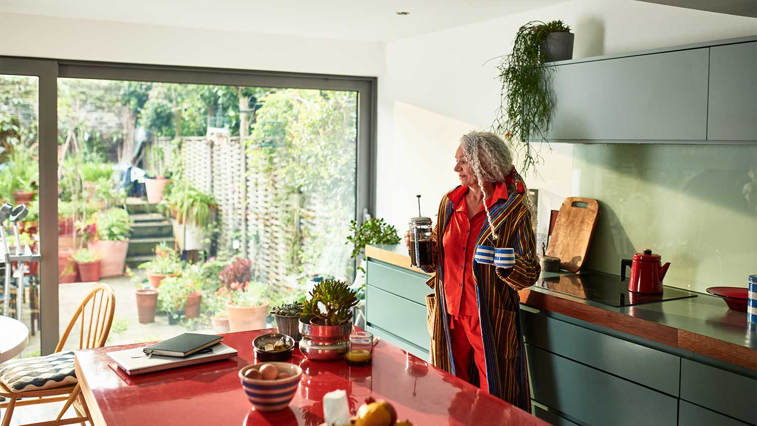A woman in her kitchen surrounded by plants
