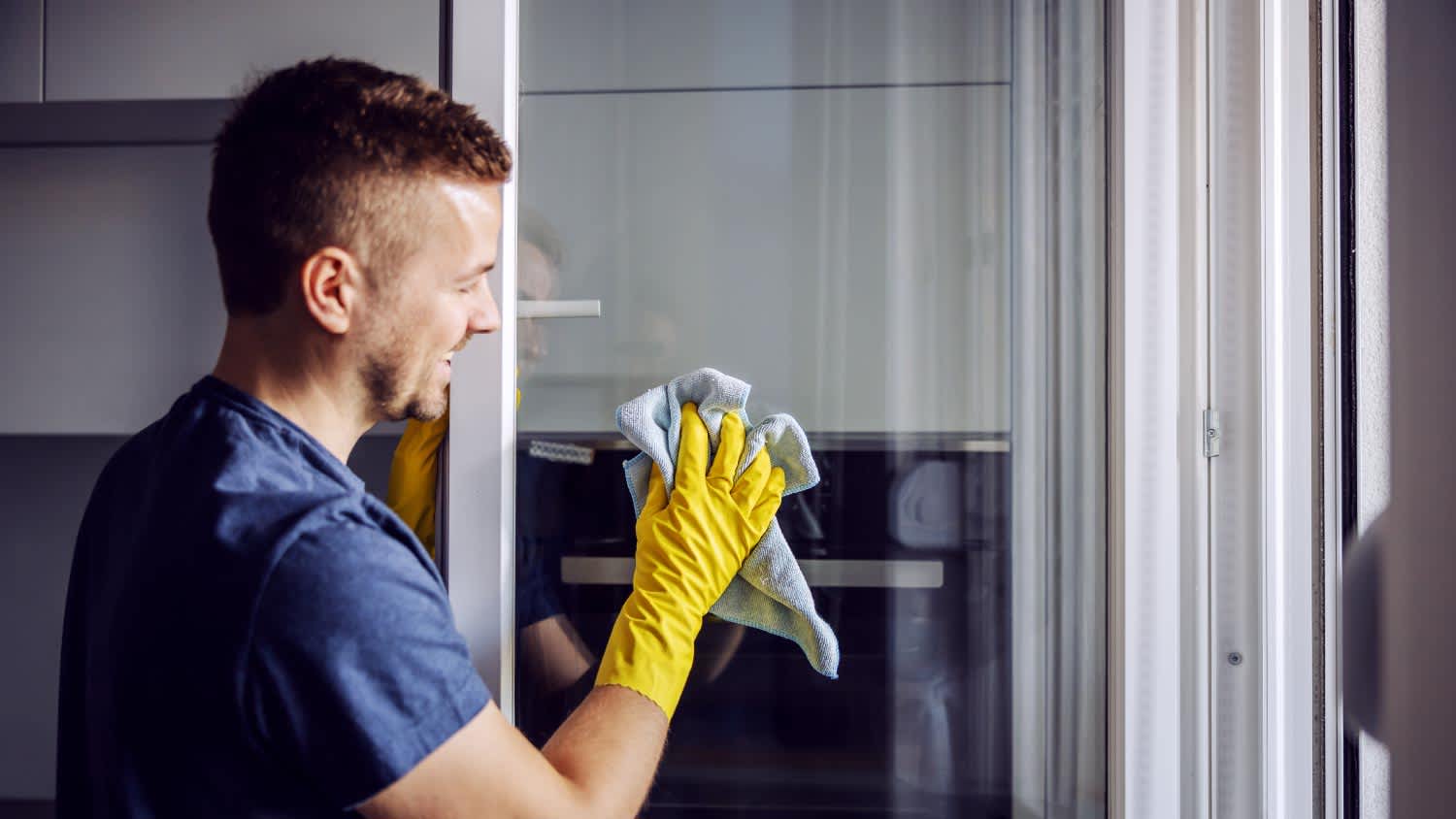 view from inside of man outside smiling and using squeegee on window