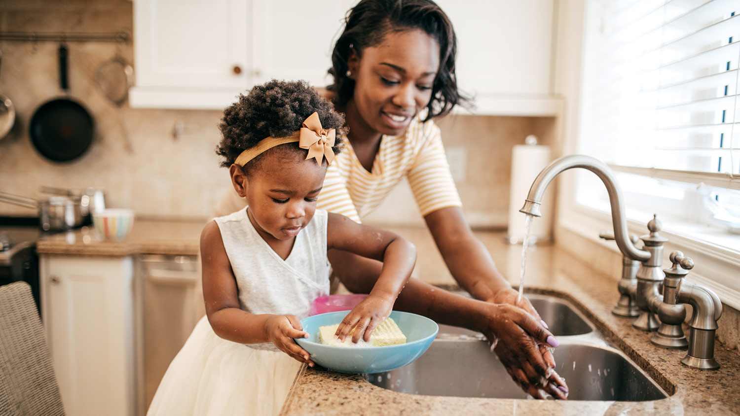 Mom and toddler wash dishes