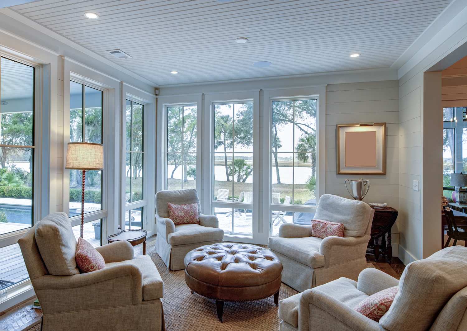 Sitting room with four armchairs facing each other, leather ottoman, shiplap accent wall and floor to ceiling windows