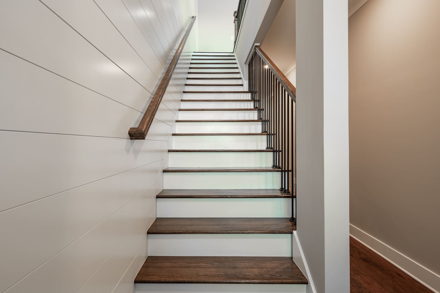 Brown and white staircase with white shiplap accent wall