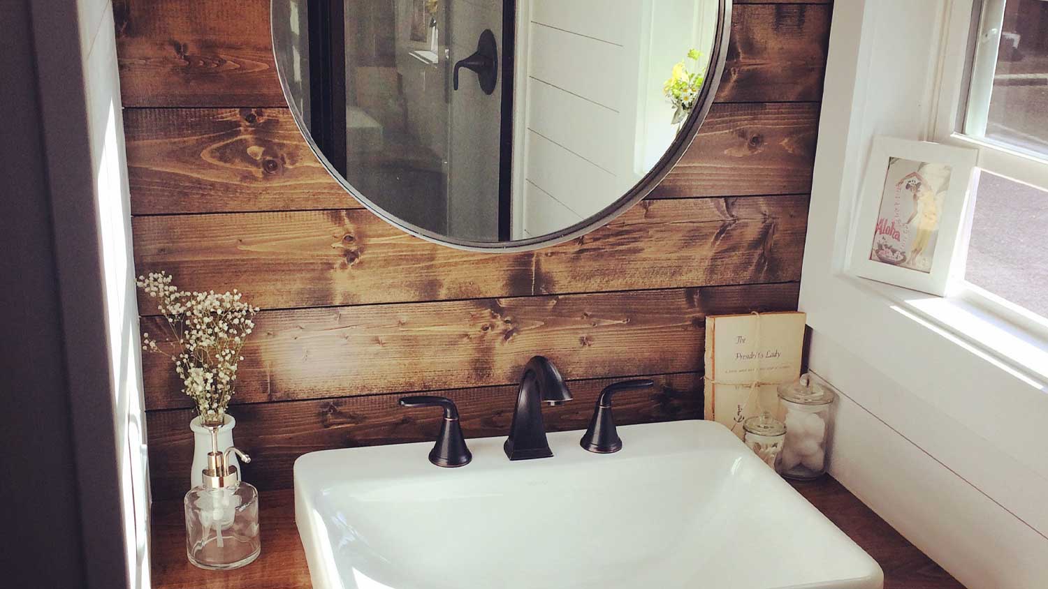 Small bathroom sink, wood shiplap accent wall, and circle mirror