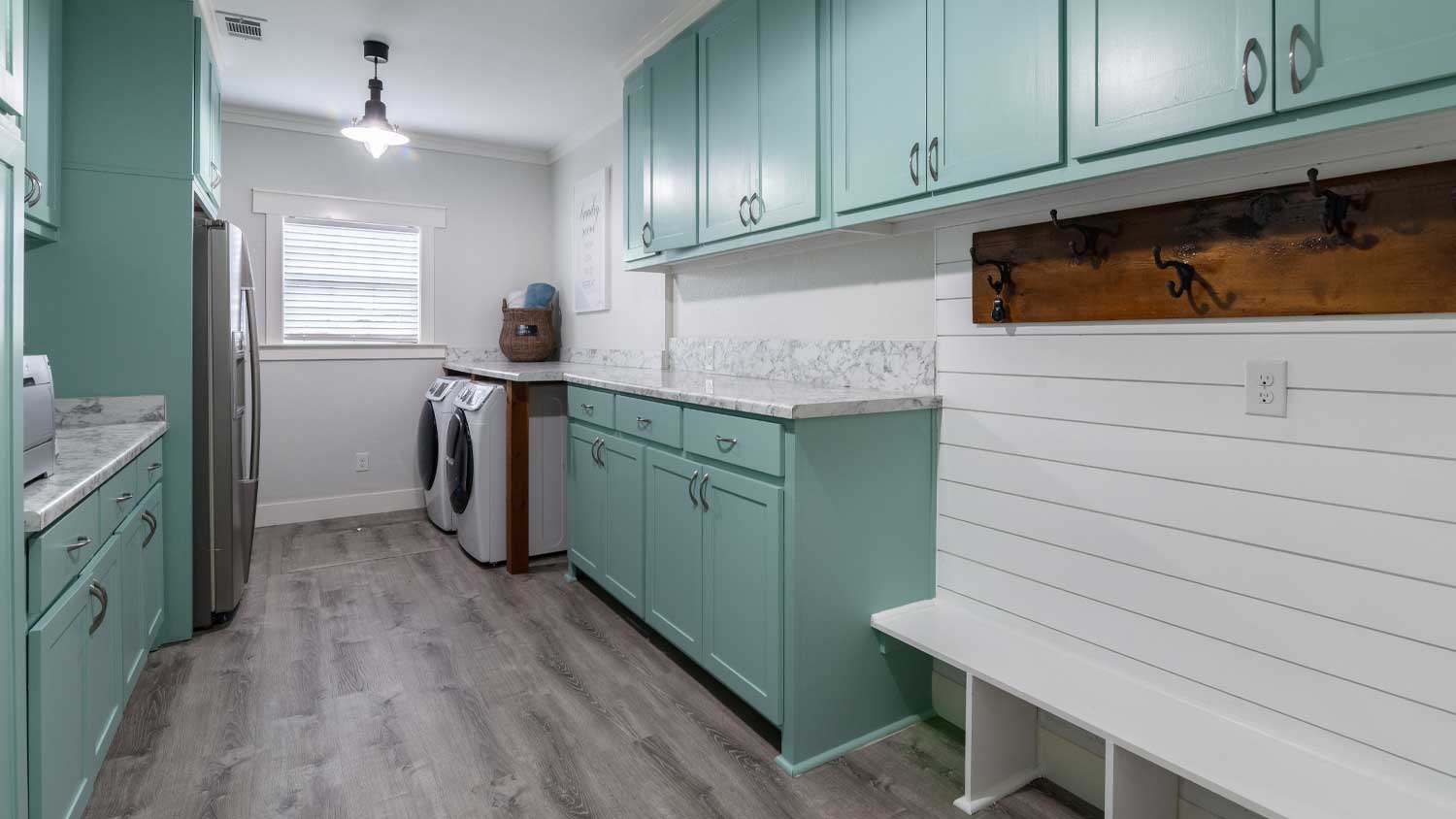Mint green and white laundry room with a white shiplap bench