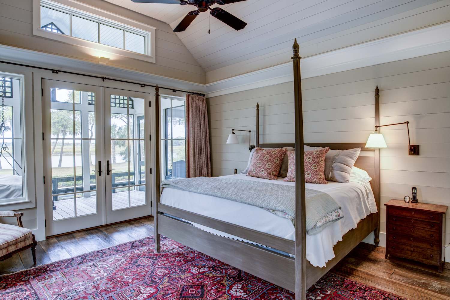 Nautical bedroom with shiplap walls, a wood bed, hardwood floors, and glass patio doors that open onto a porch