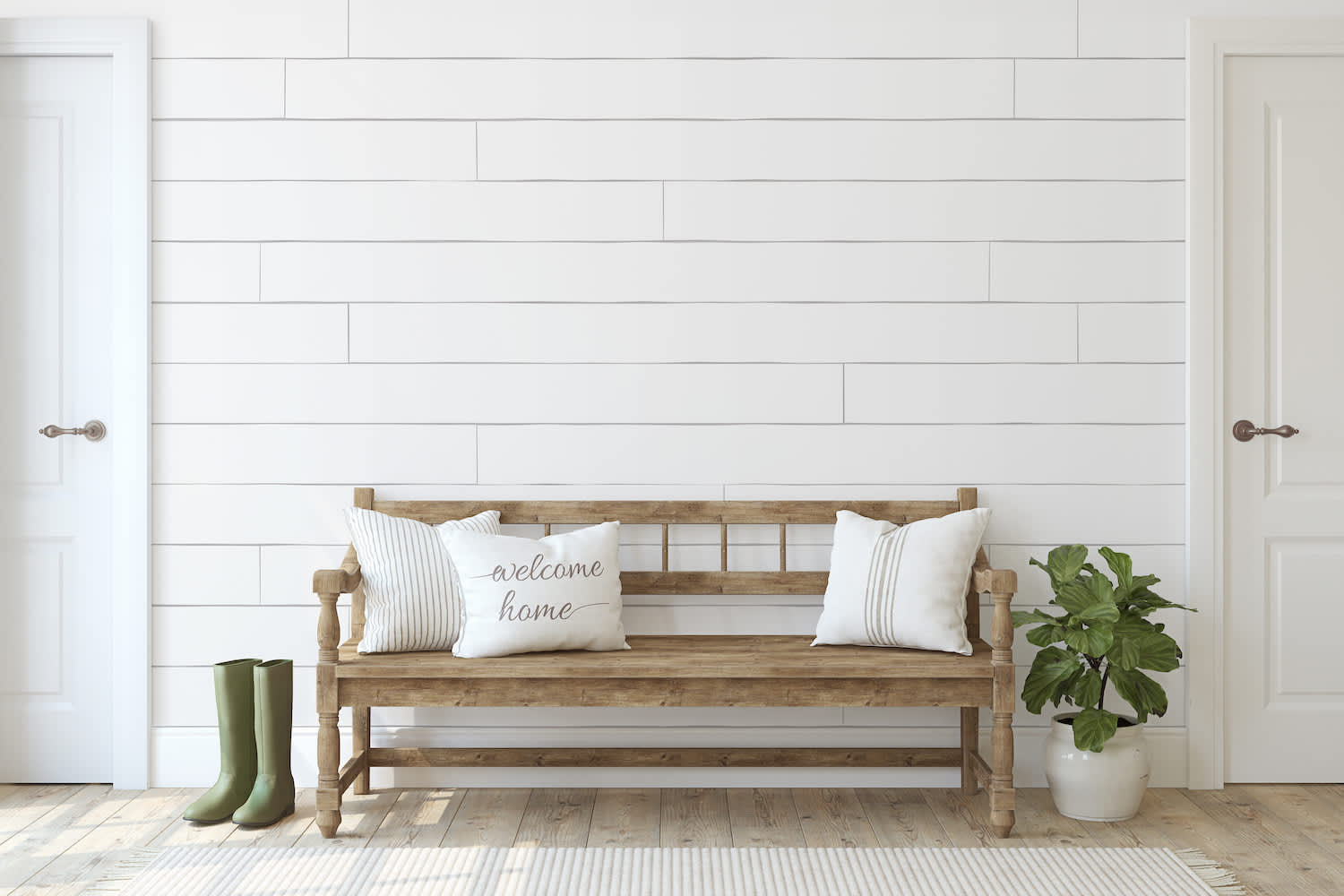 Entryway with boots, a plant and a wooden bench with throw pillows in front of a white shiplap accent wall between two doors
