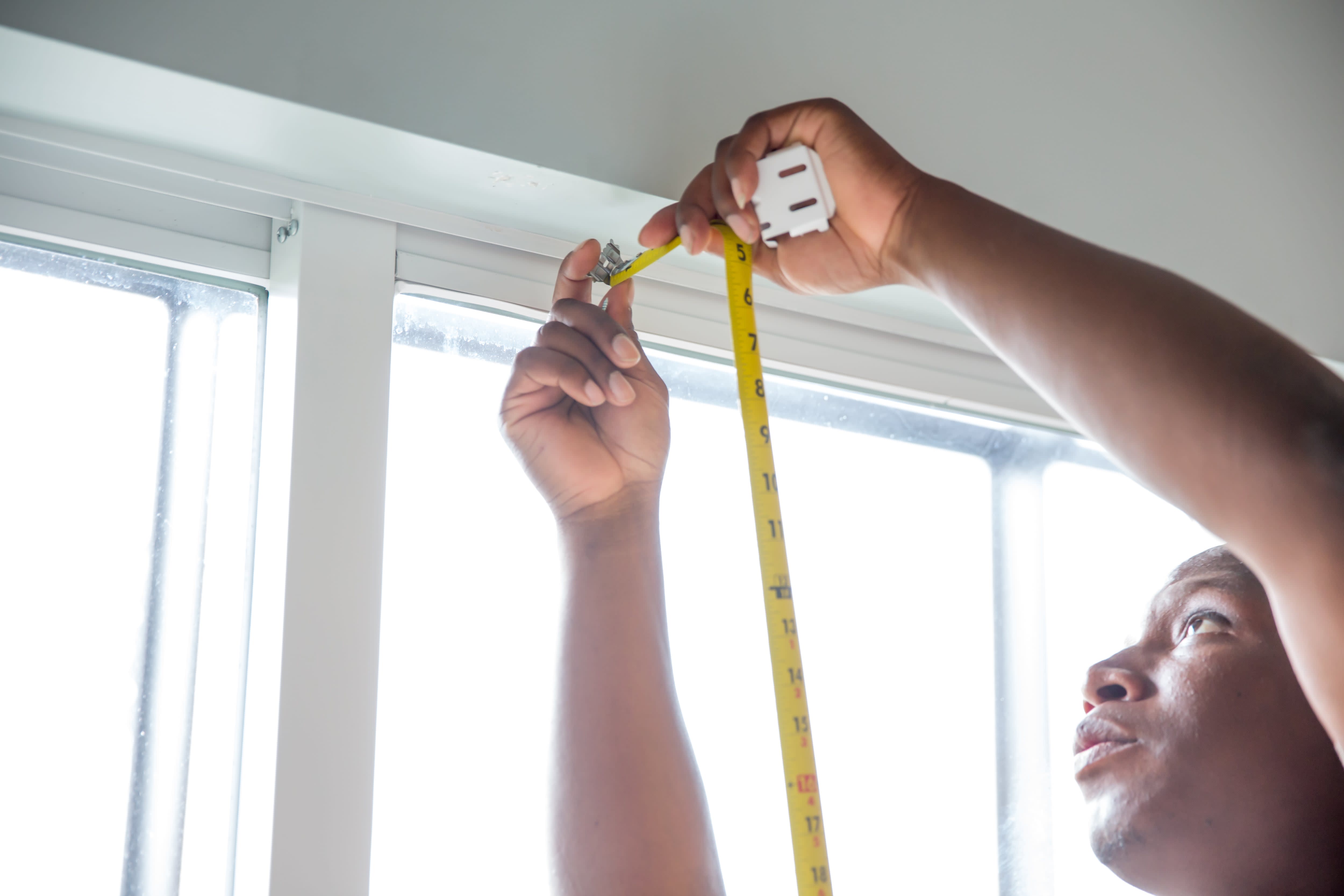 Man measuring for blinds using tape measure