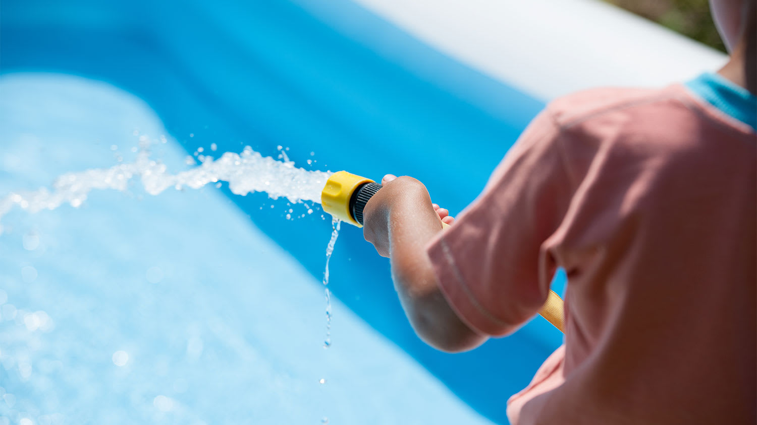 A boy fills a wading pool