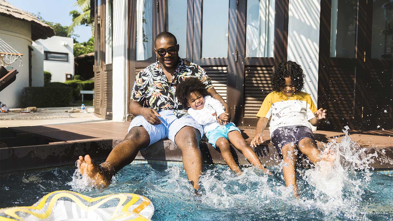 A family sits on the edge of a swimming pool