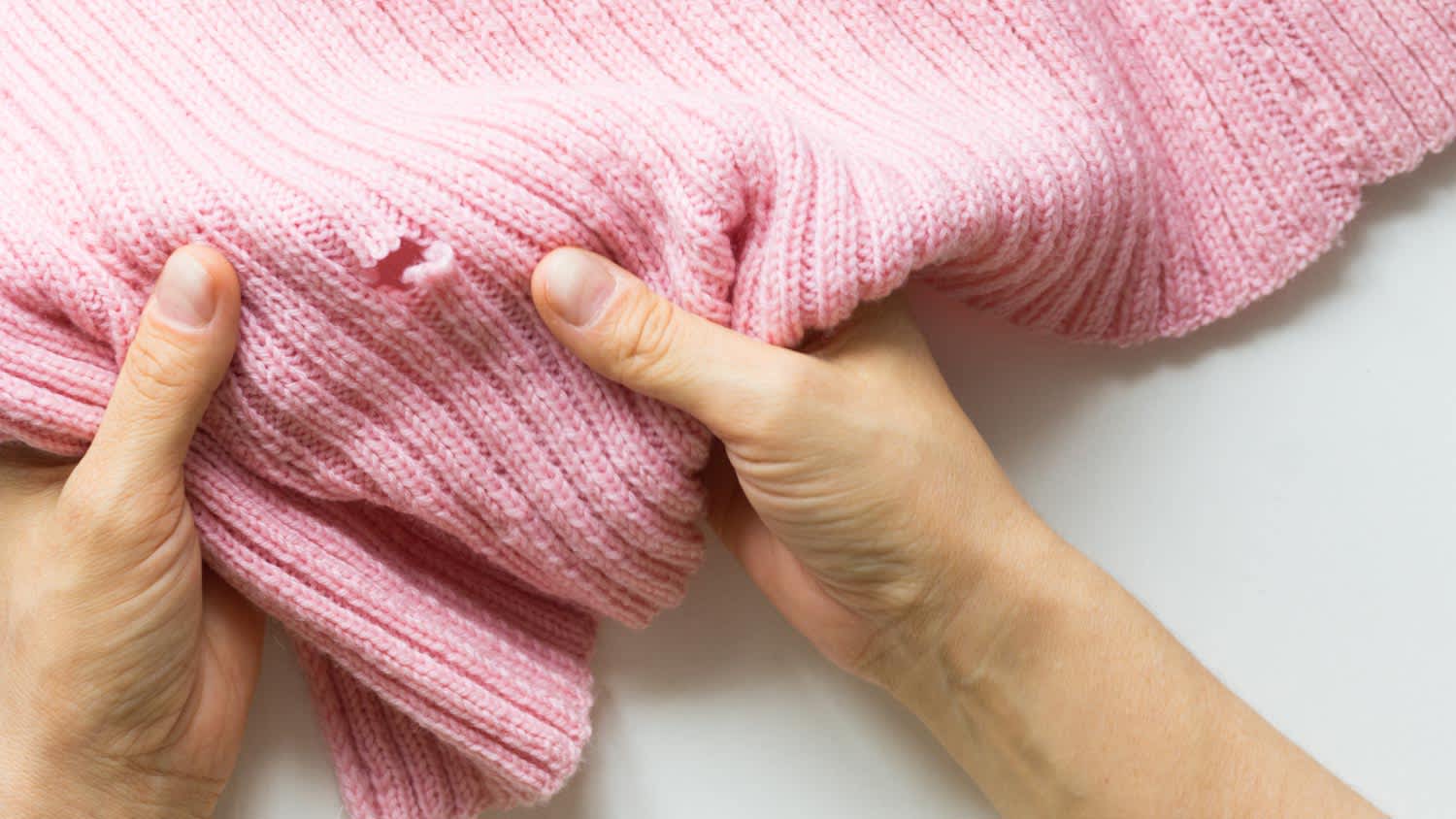 A woman holding knitted thing with hole made by moth