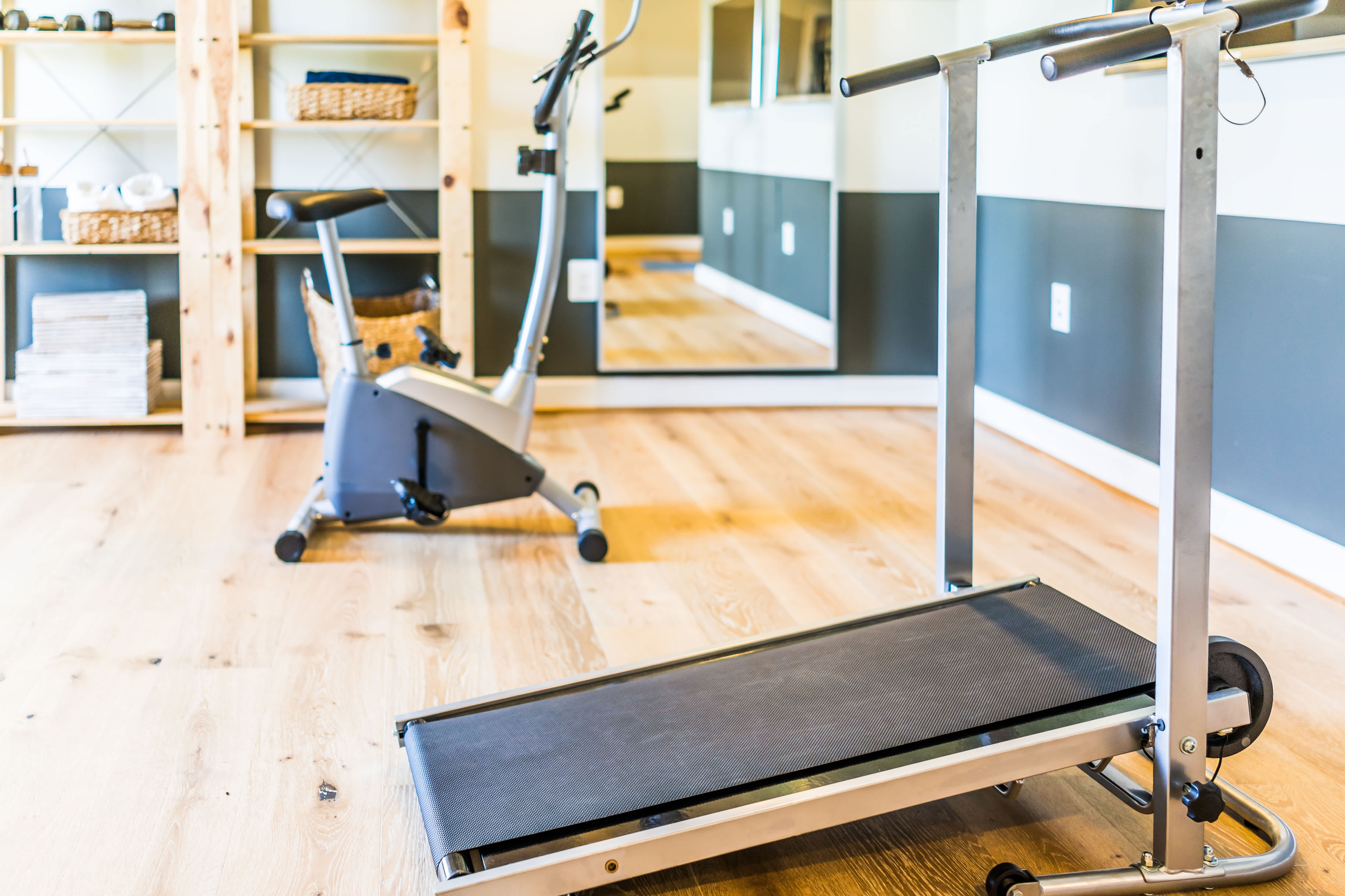 Simple modern home gym with a treadmill, stationary bike, and mirror