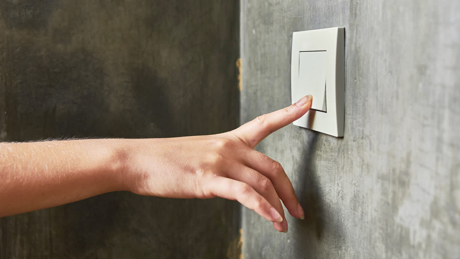 A woman’s hand turning off a light switch