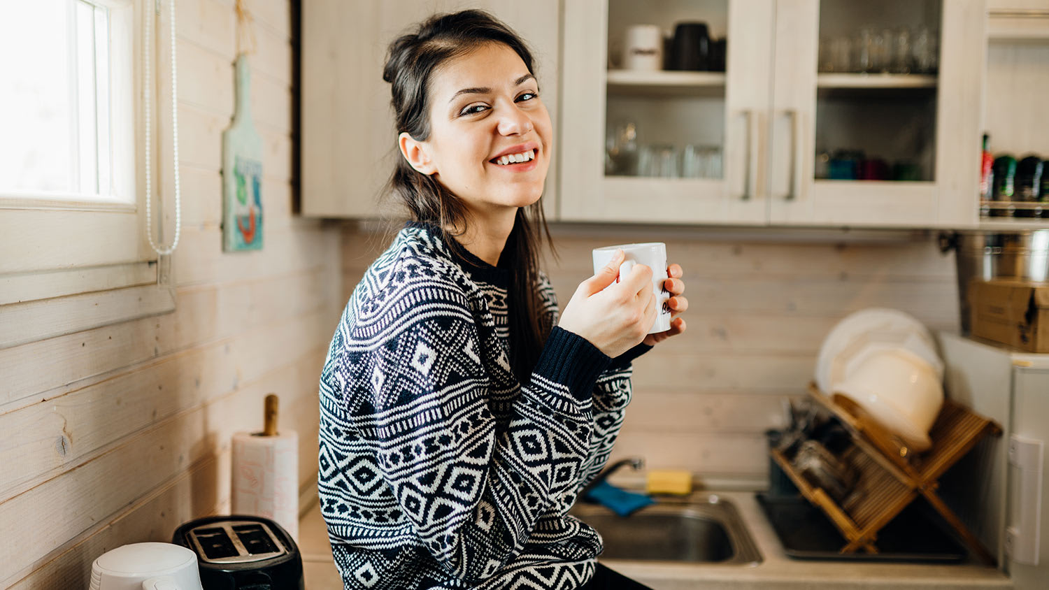 Woman sitting on counter in tiny house kitchen