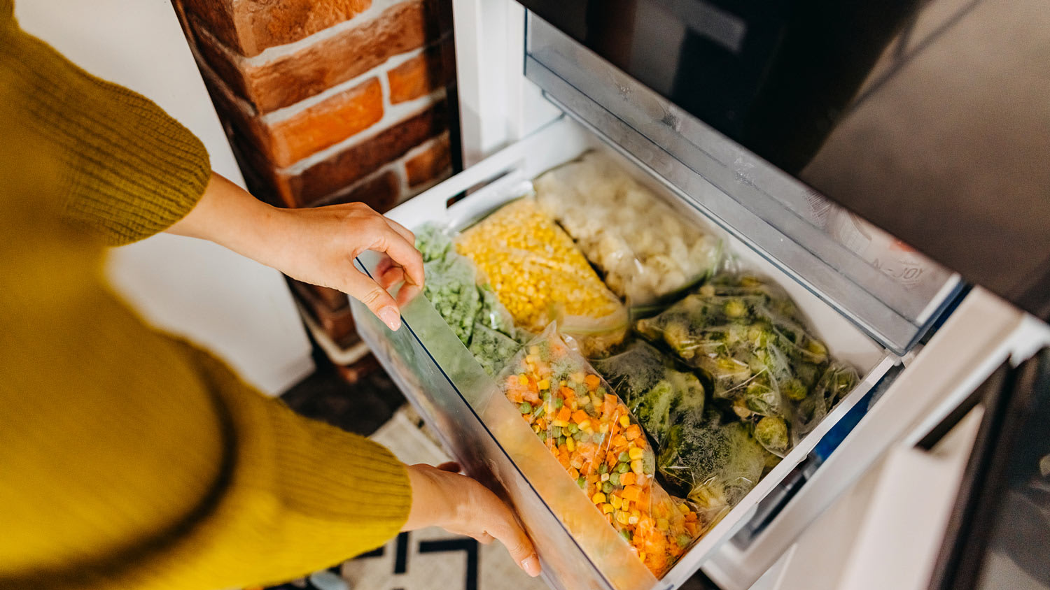 A woman’s hands opening freezer drawer