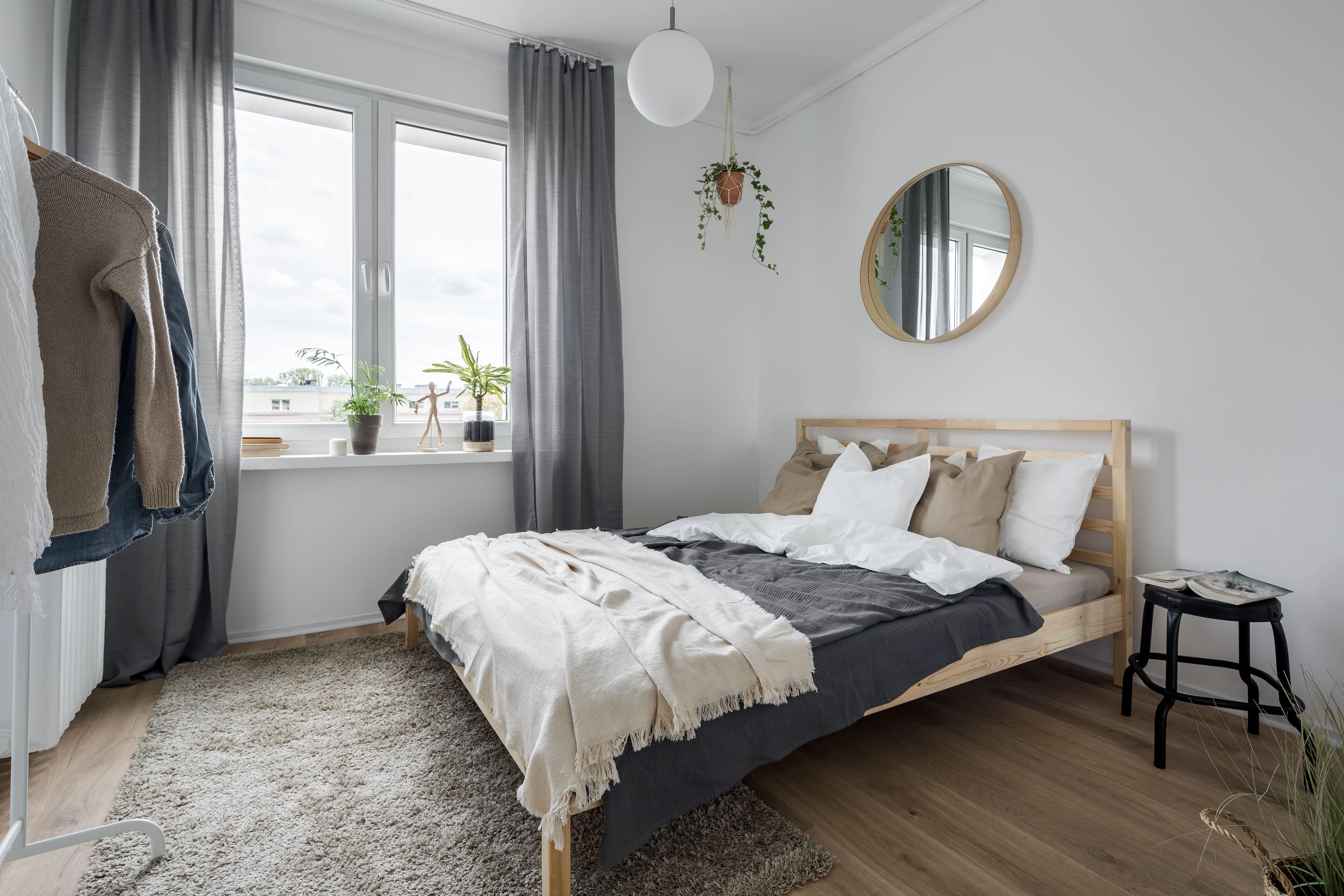 A small bedroom with tall curtains starting at the ceiling