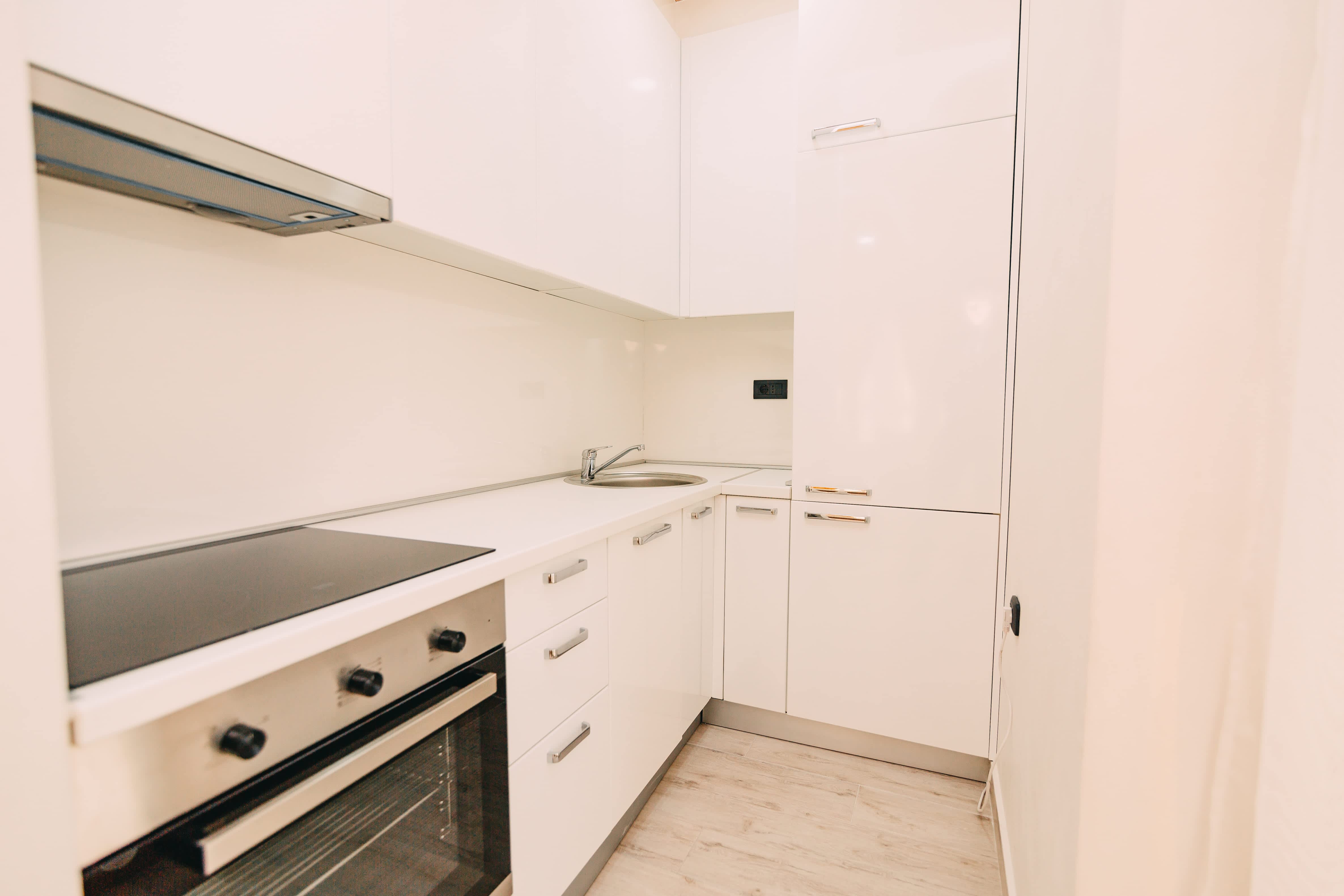 An all-white kitchenette with large floor-to-ceiling cabinets