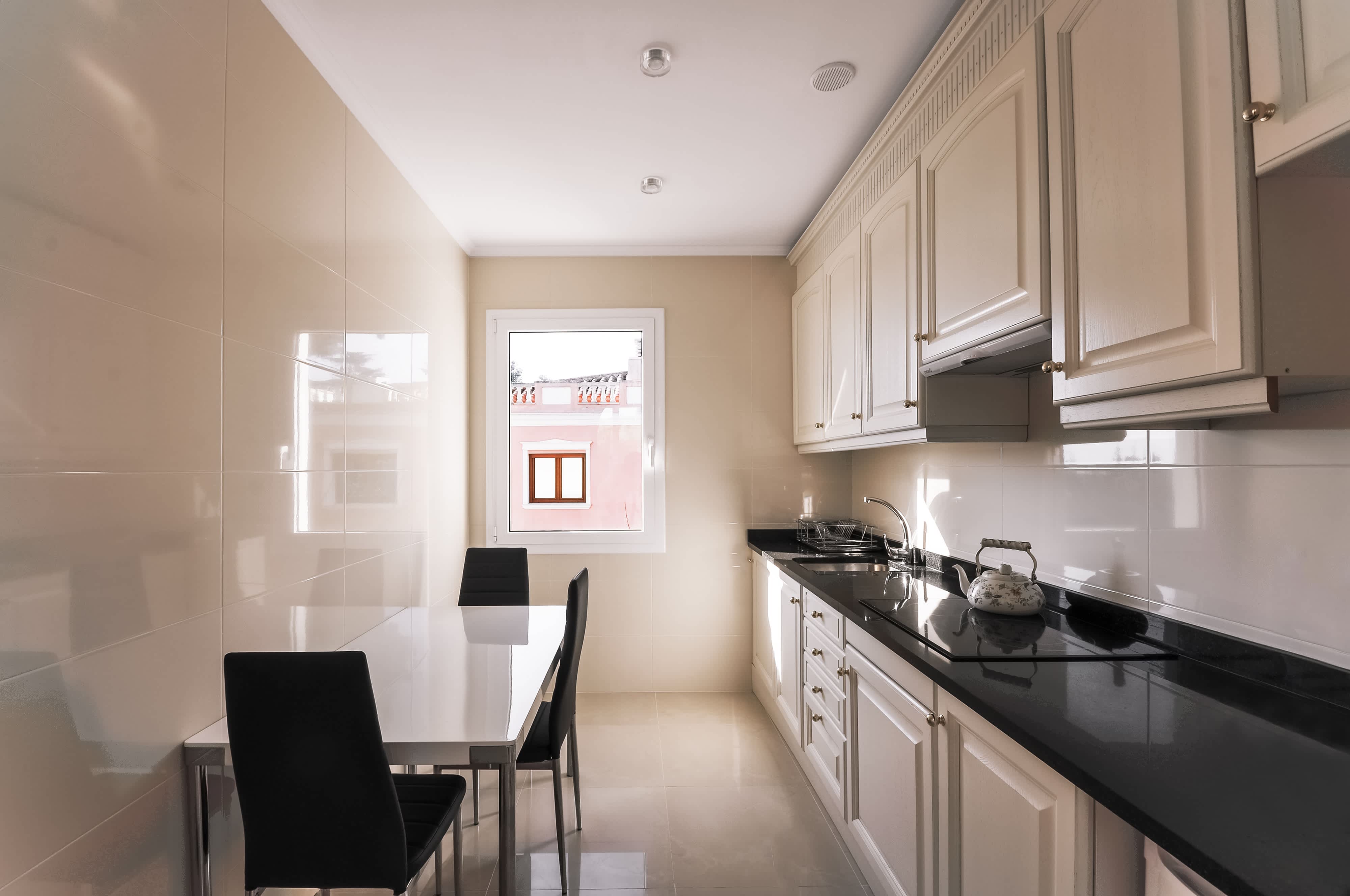 A basic galley kitchen with a window and dining room table