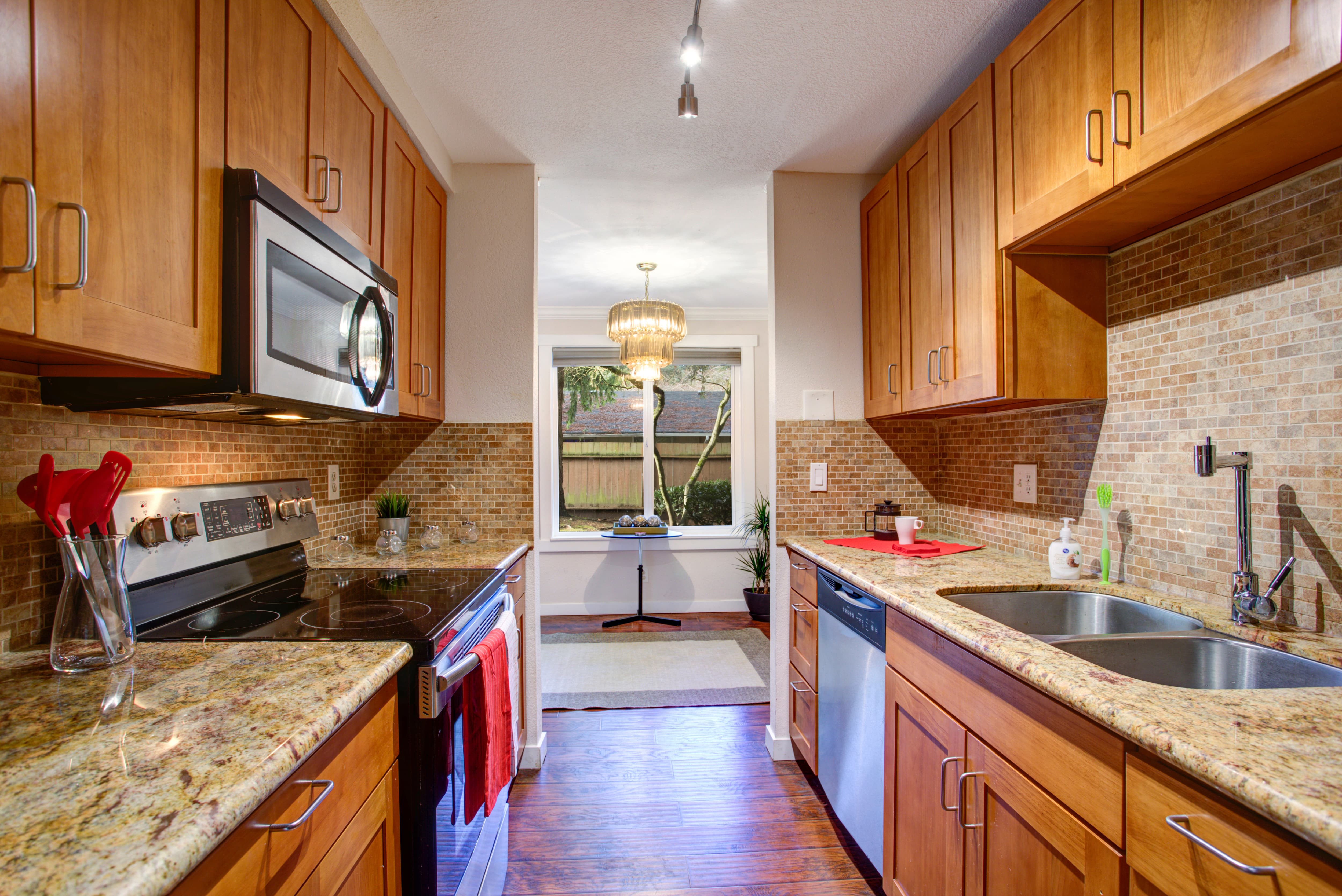 A galley kitchen with natural wood cupboards and small stone tile backsplash