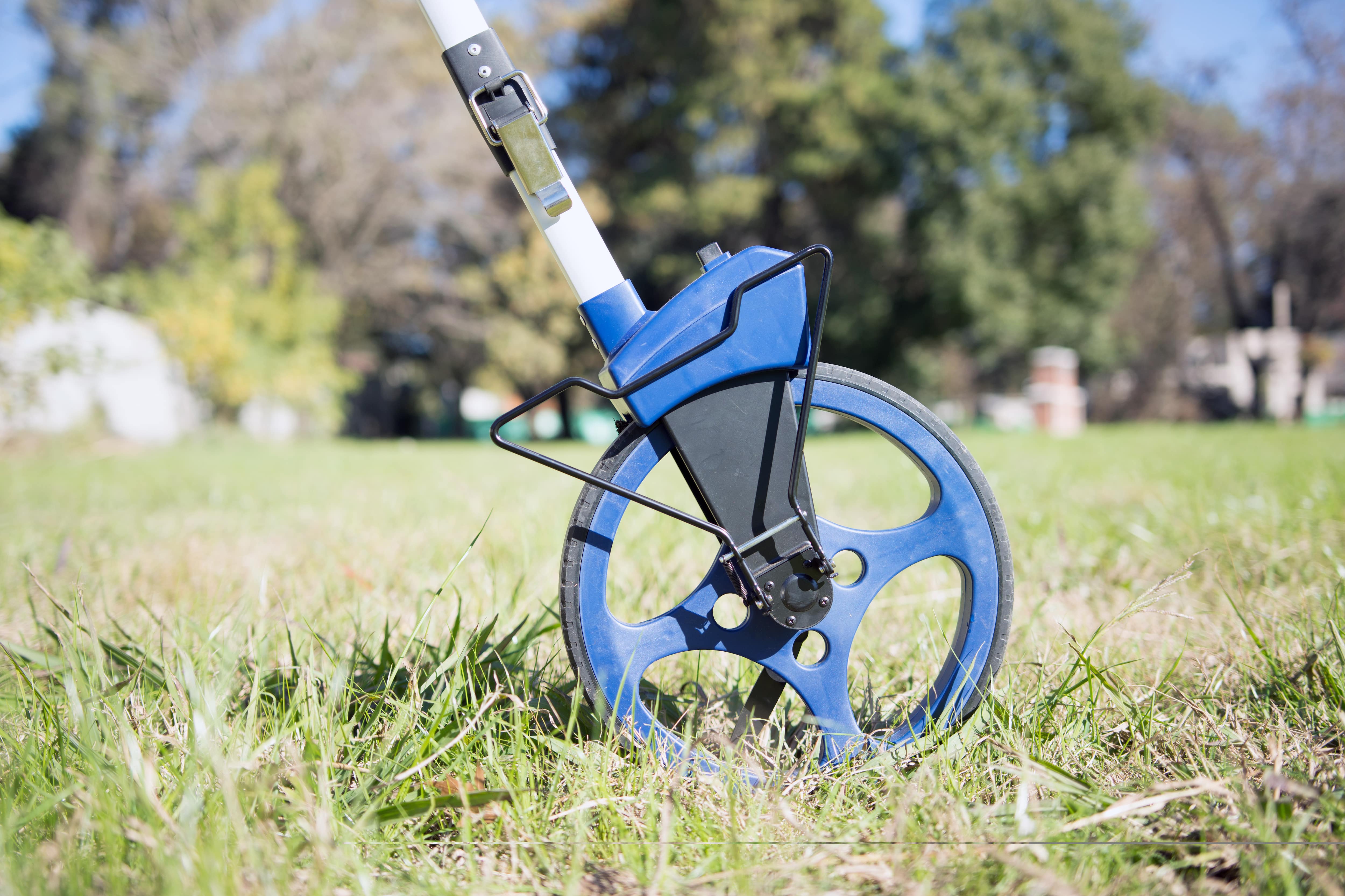 Using measuring wheel to take measurements of yard