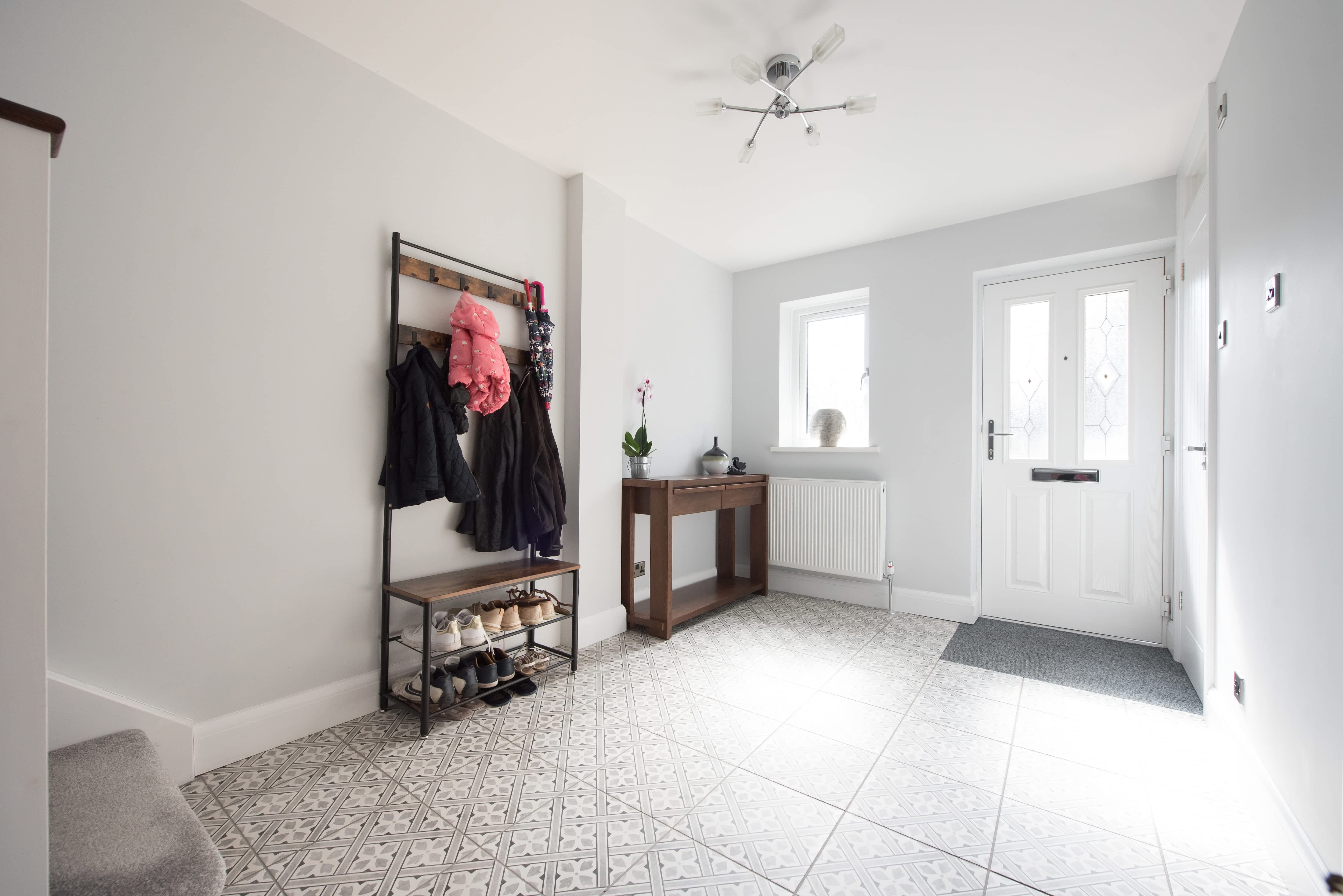 An entryway with a coat and shoe rack and patterned tile floors