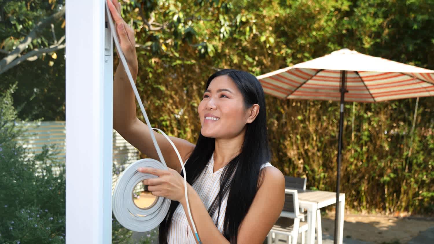 A woman weatherstripping a door