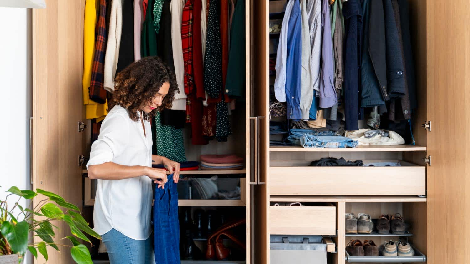 Woman in front of her closet folding her jeans
