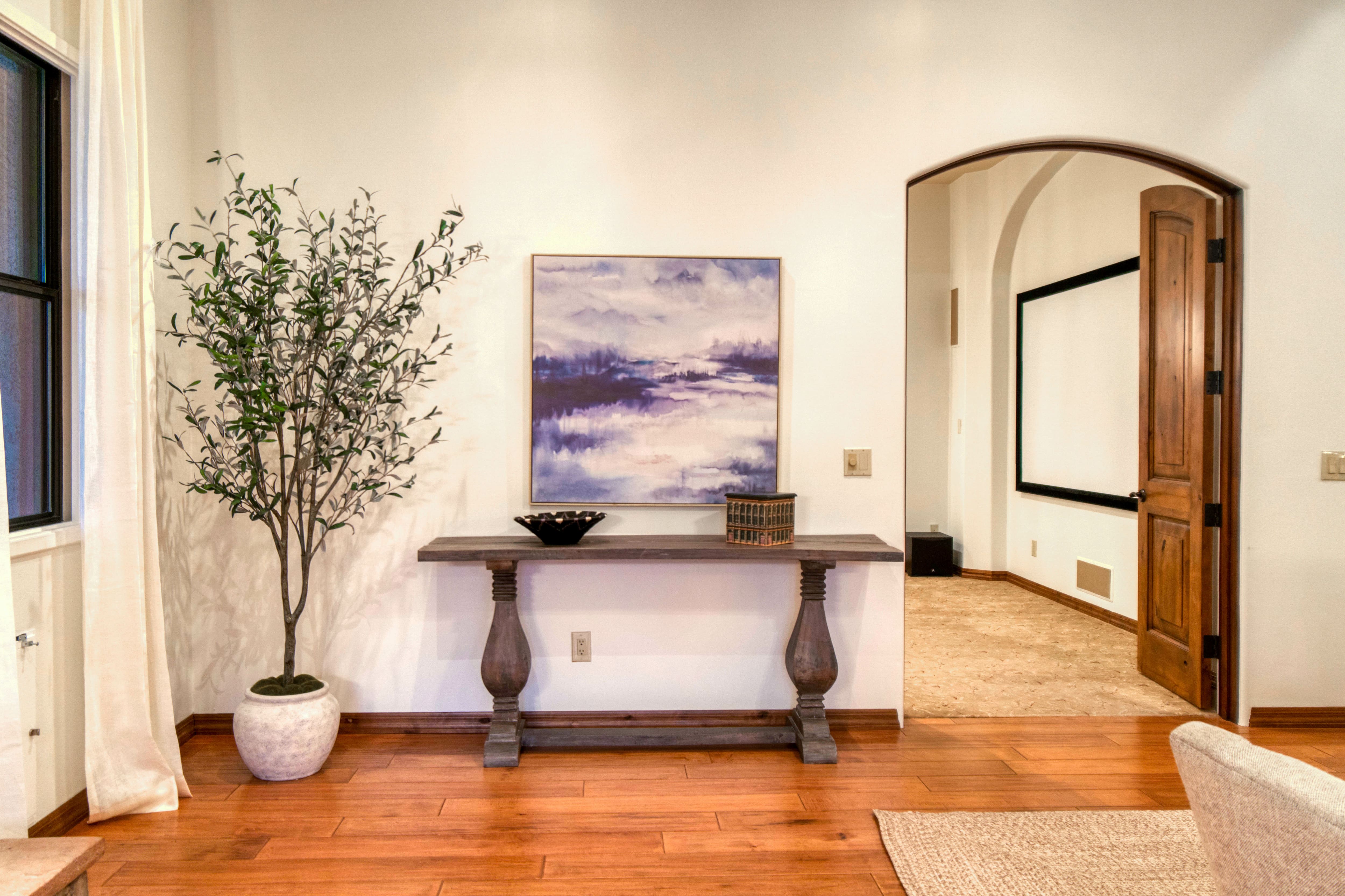 A home entryway with an accent table and a unique framed painting above it