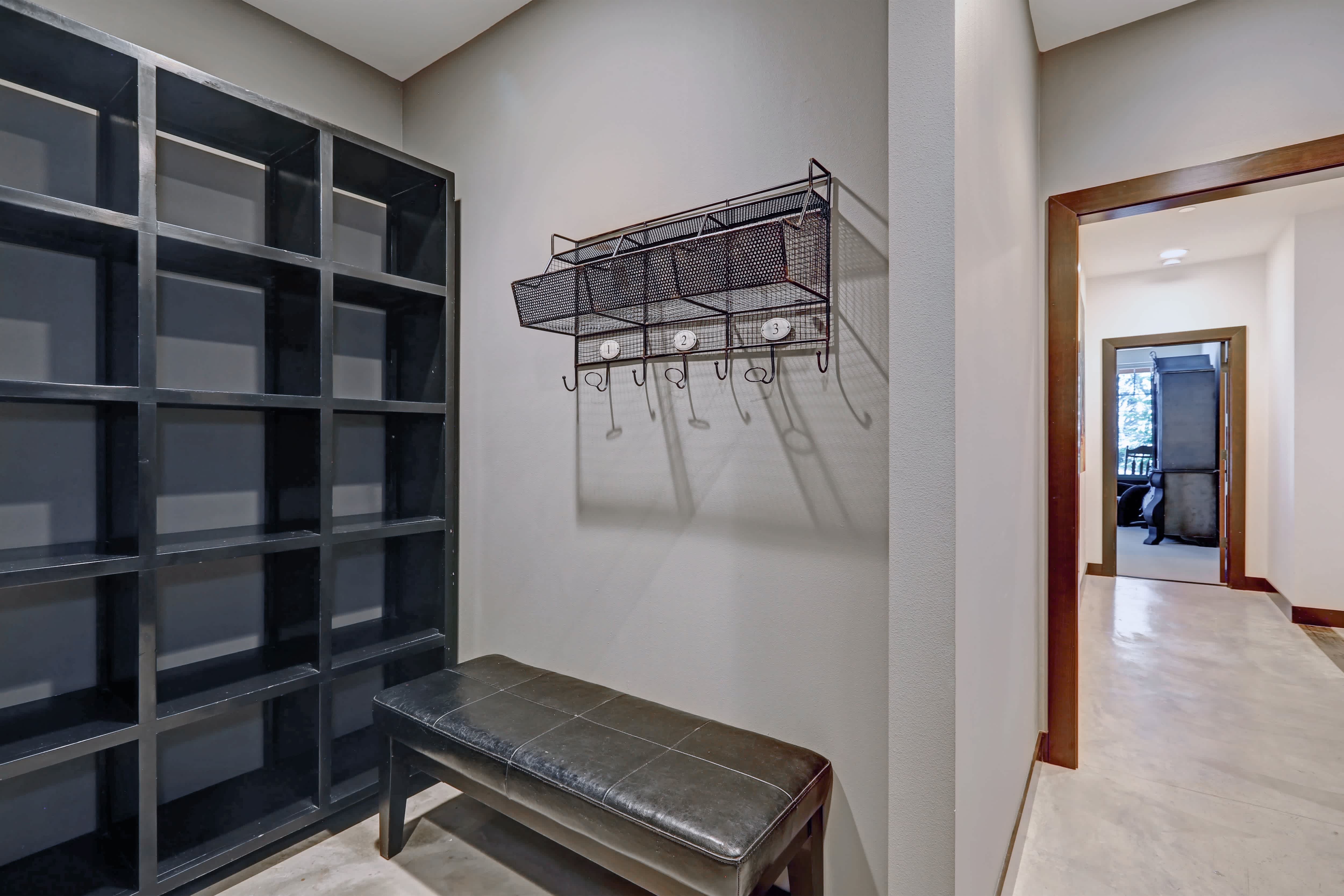A gray-toned residential entryway with black cube shelves, a bench, and a mail holder