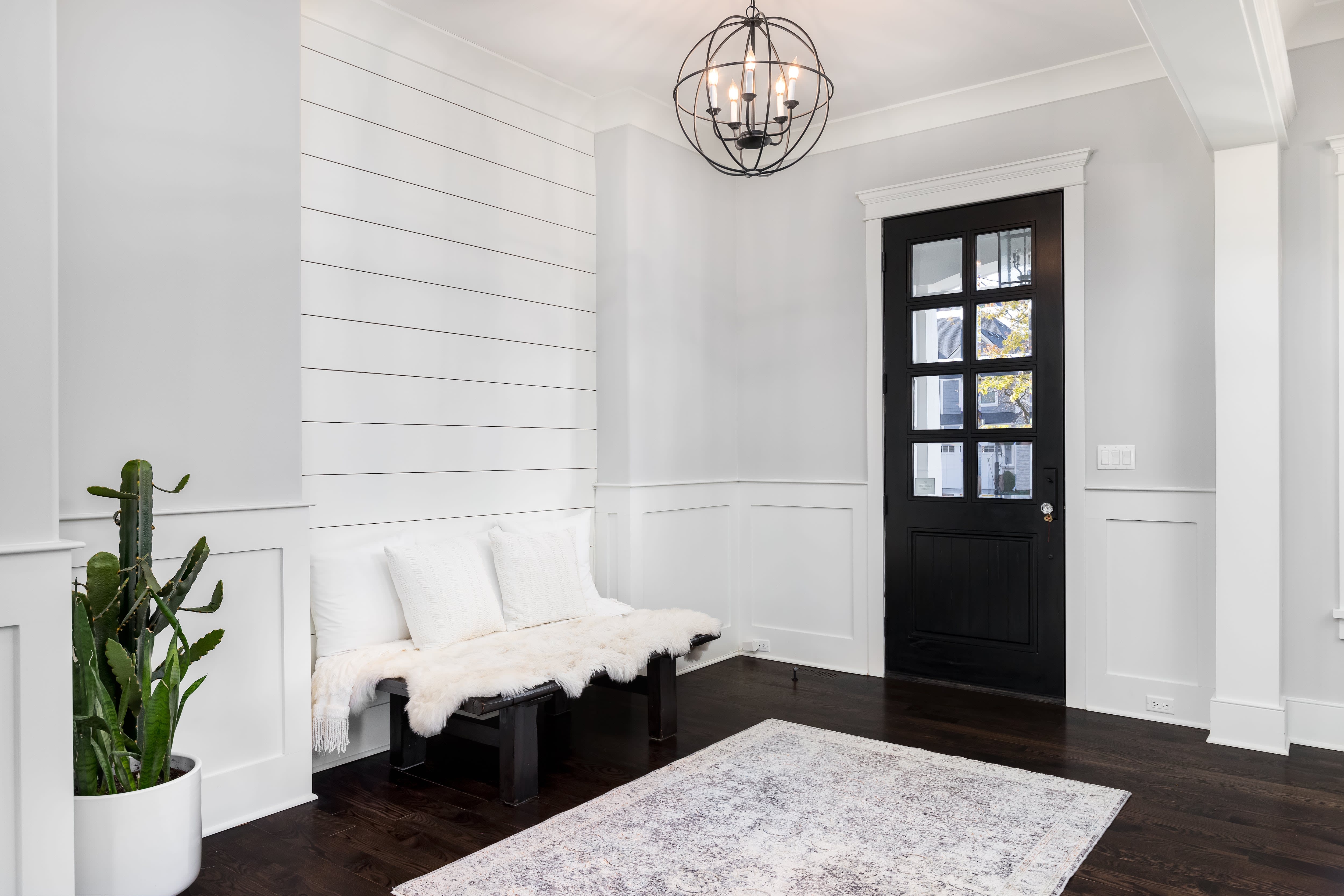 A home foyer with white walls, a black door, and dark hardwood floors