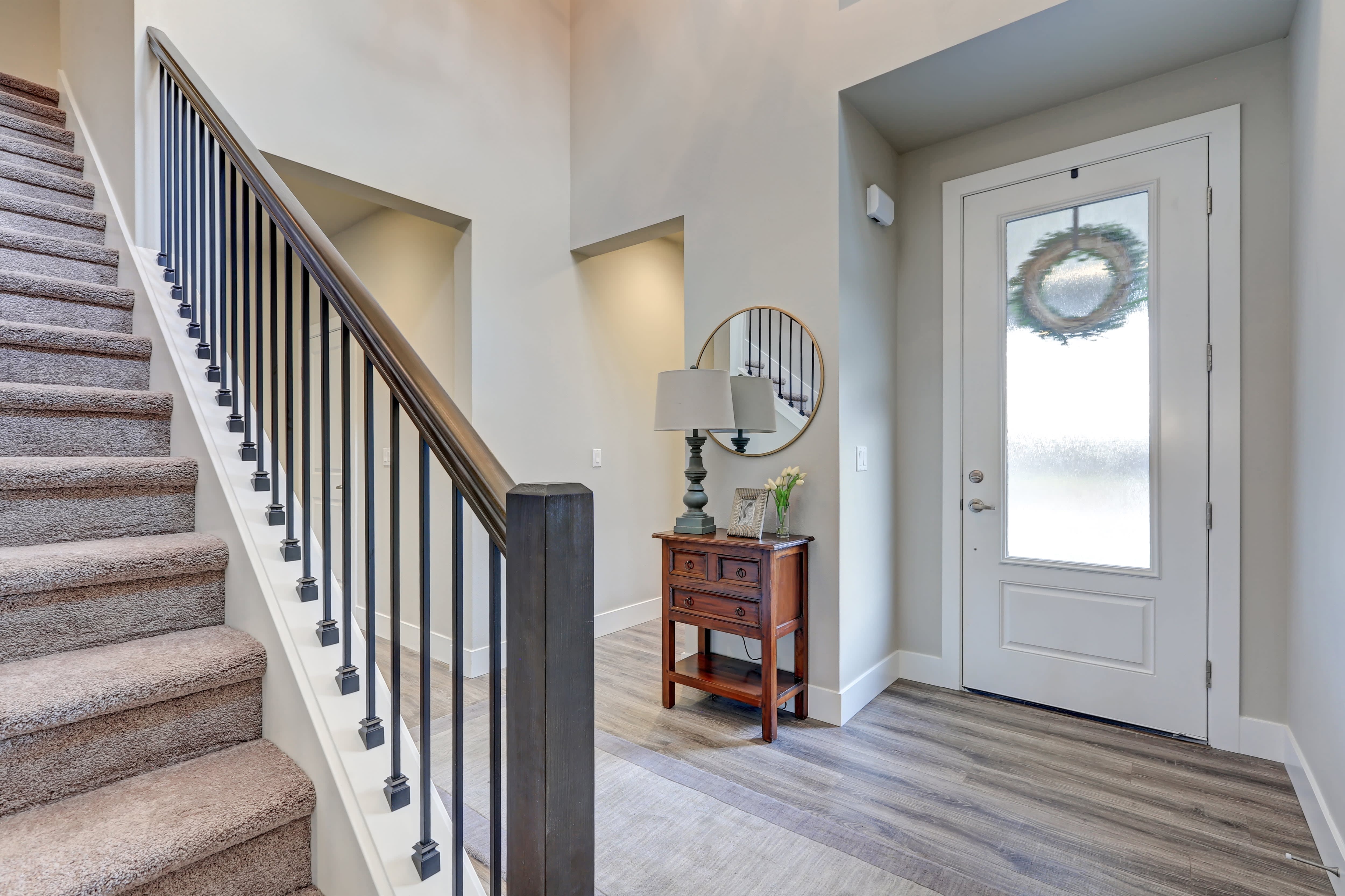 A gray foyer with a lamp and picture frame on top of a small side table